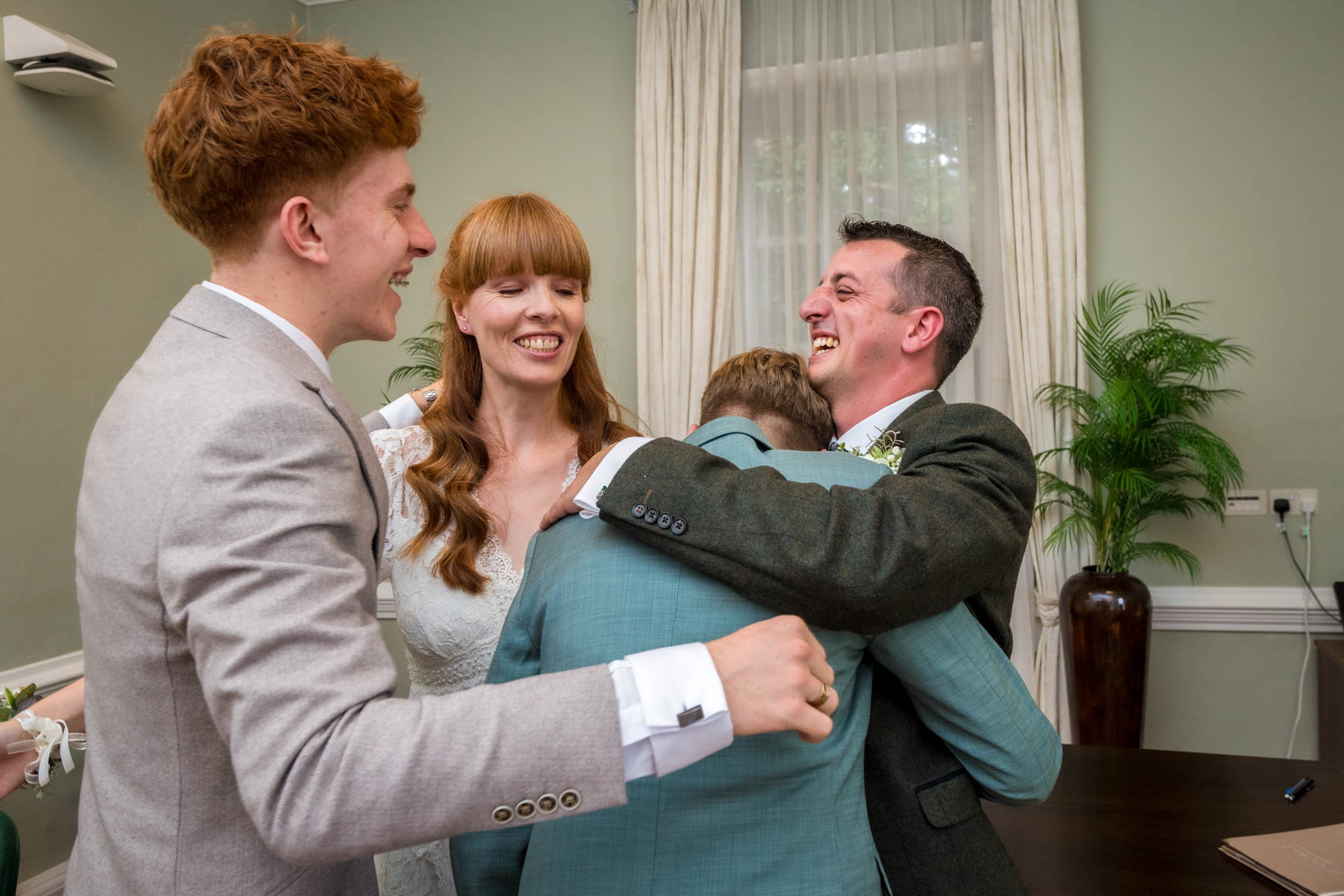 Teenage boy overcome with emotion and having cuddle with bride and groom at wedding in Richmond