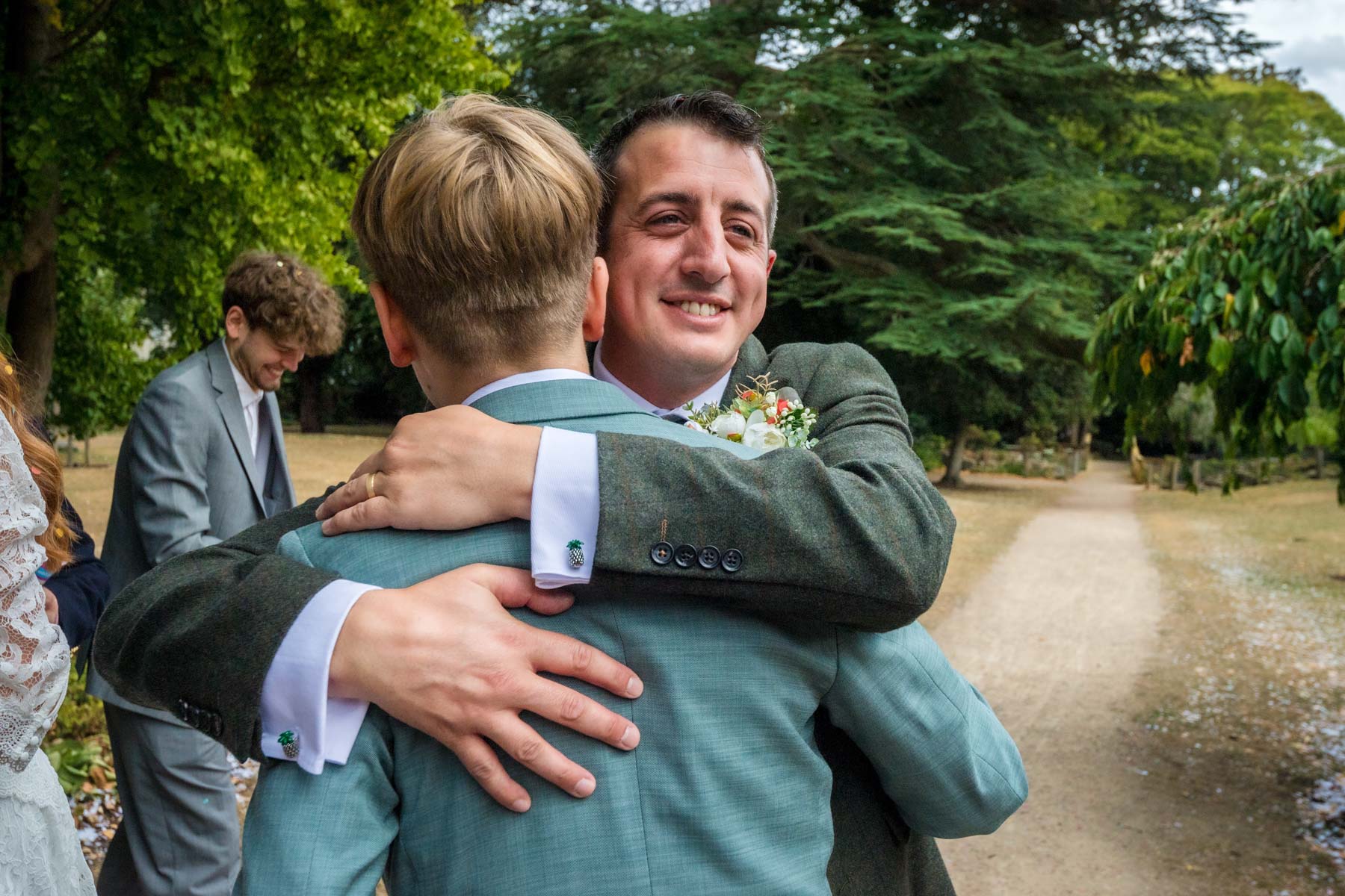 Groom hugging teenage boy at wedding in Twickenham
