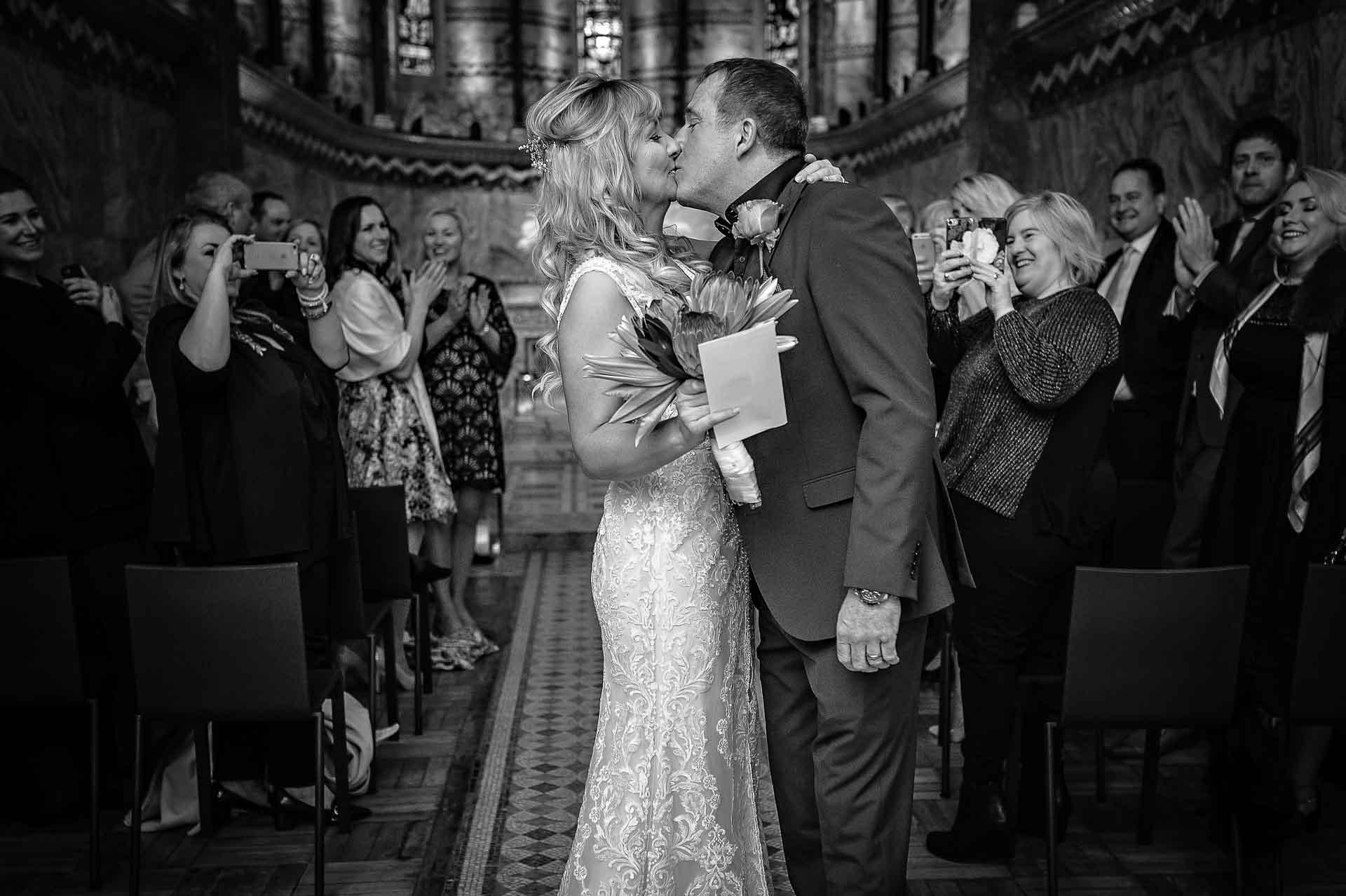 Black and White Photo of Couple Kissing in front of guests at wedding