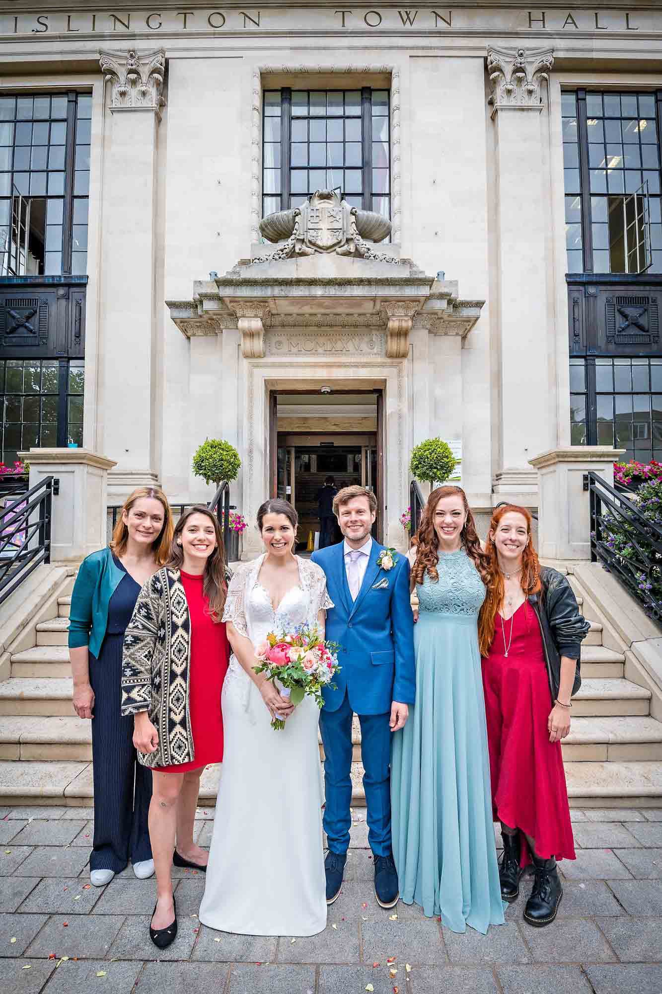 Bride and groom pose with friends outside Islington Town Hall