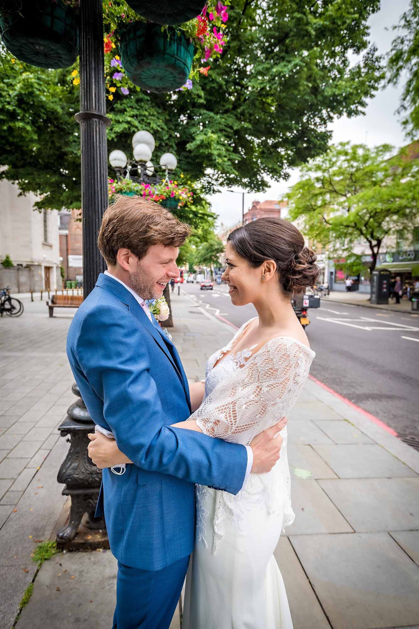 The bride and groom greet each other in an embrace on Upper Street, Islington