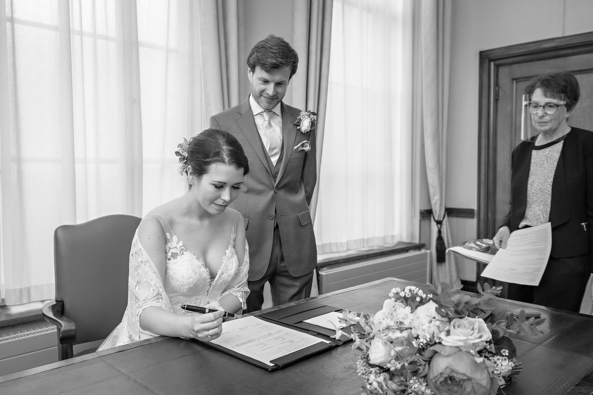 The bride signs her wedding schedule whilst the groom watches on