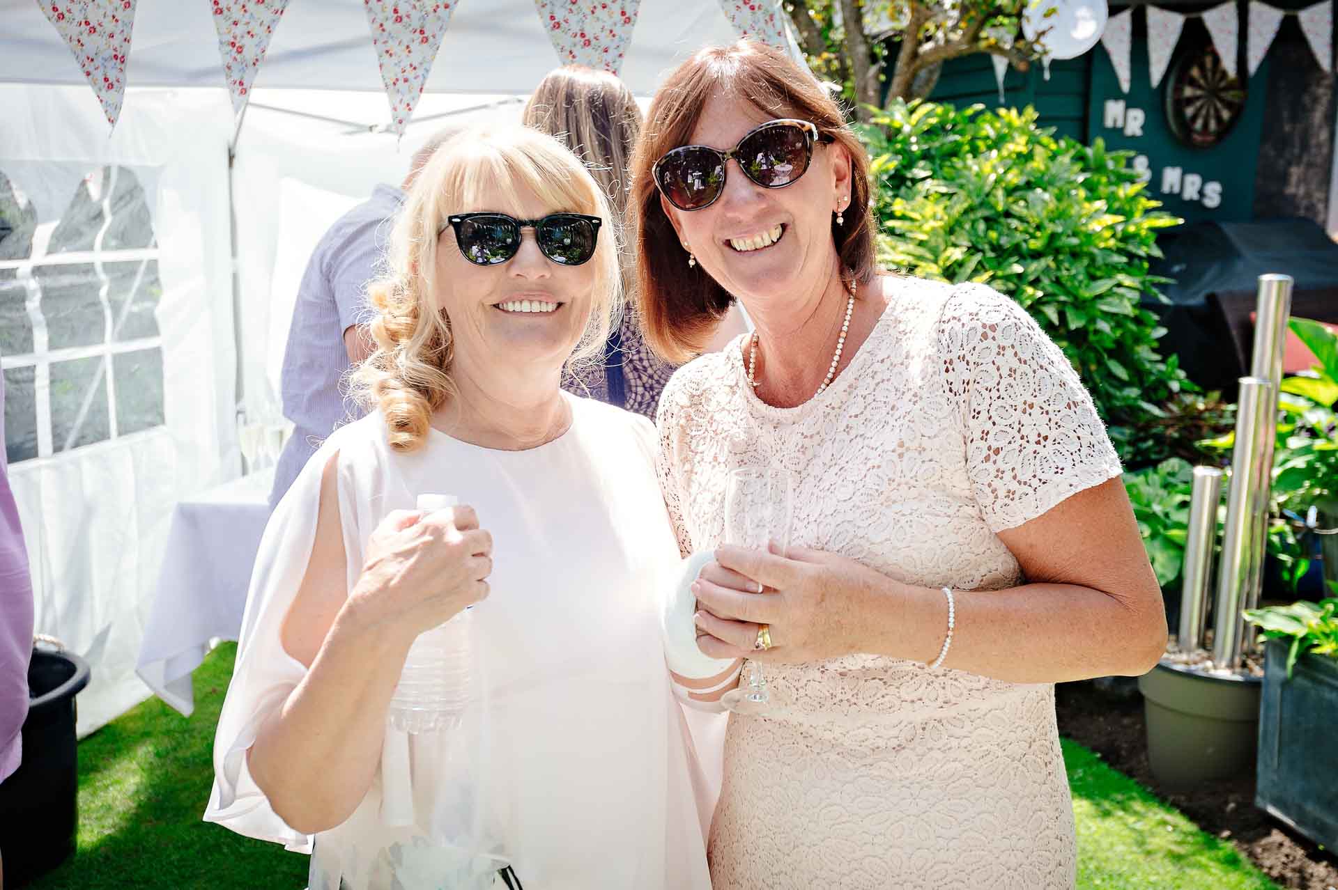 Guests in Glasses Smiling at Sunny Wedding