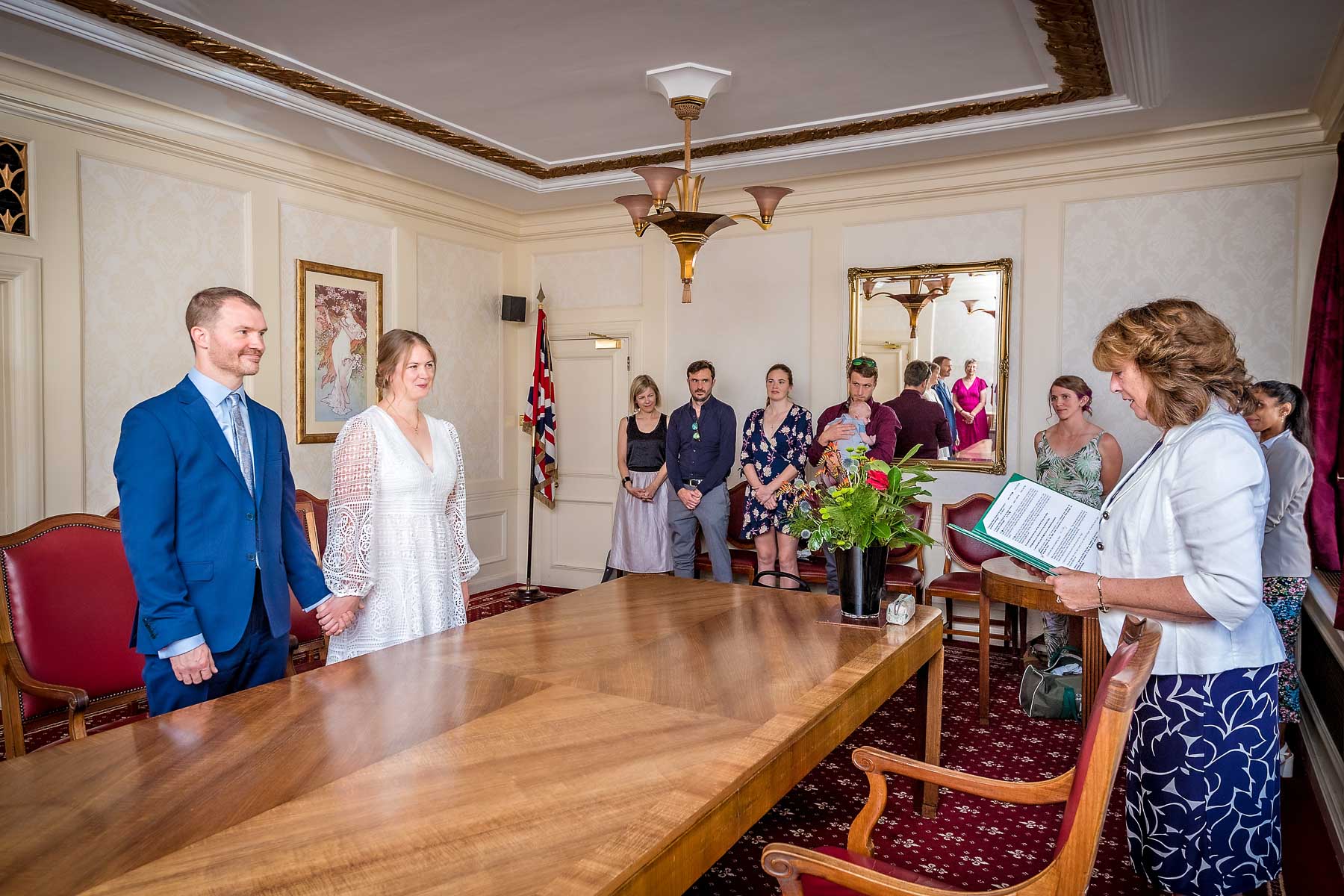 Couple facing registrar across wide wooden table in the Victoria Room at Wandsworth Town Hall