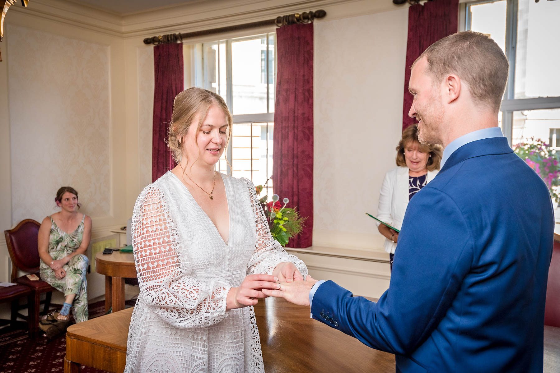 Bride placing wedding ring on groom's finger in the Victoria Room at Wandsworth Town Hall