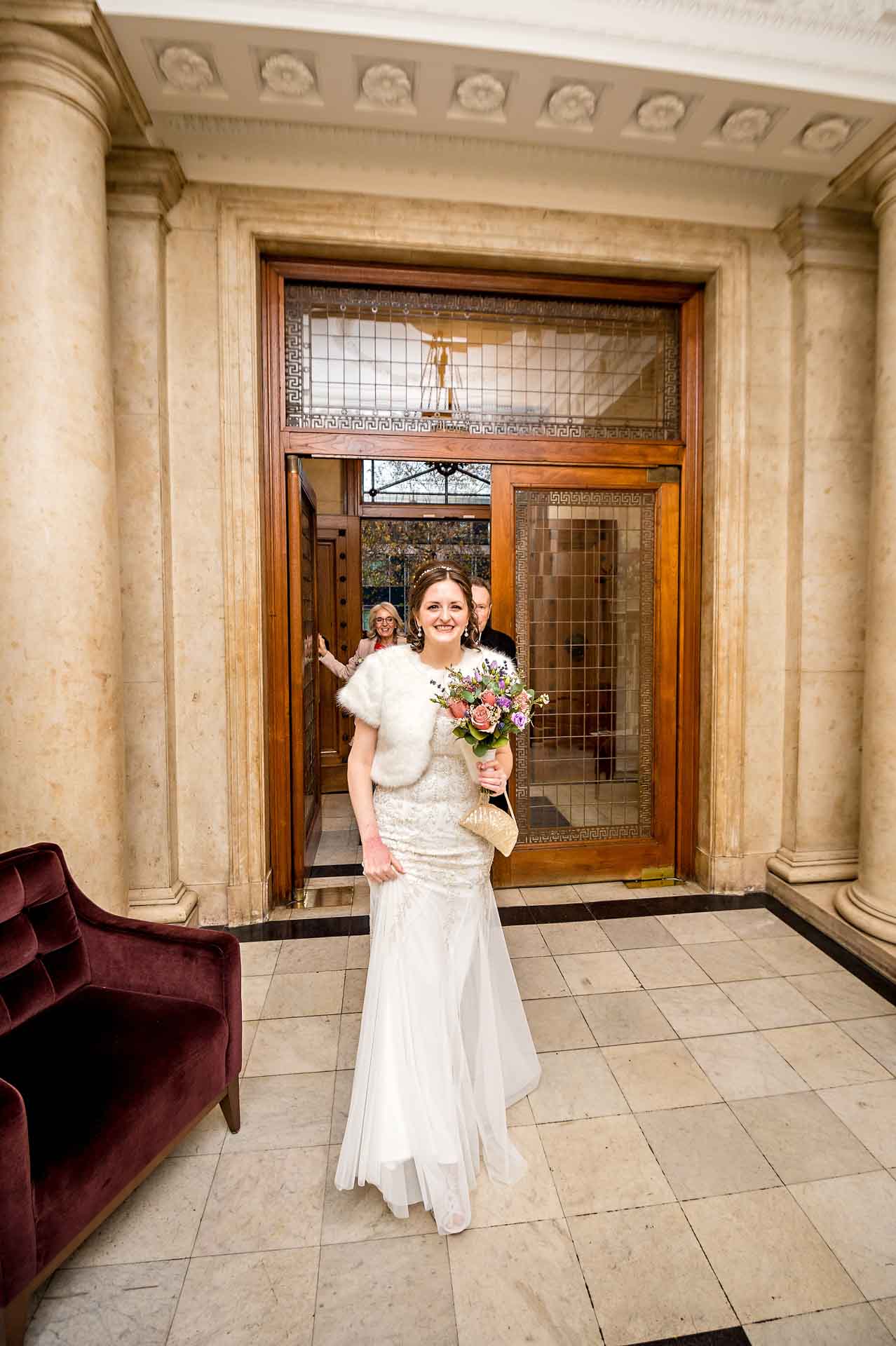 Bride walking through entrance hall of ornate Old Marylebone Town Hall register office in London