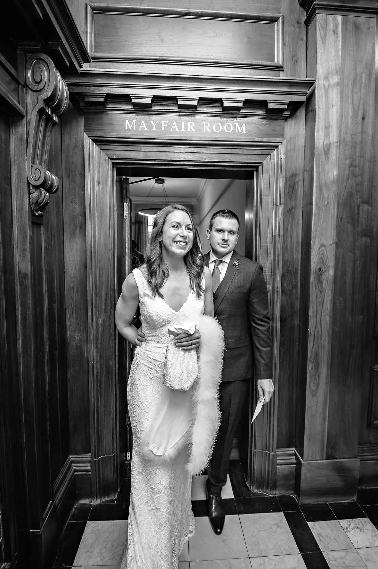 Happy bride and serious groom leave Mayfair Room after Old Marylebone Town Hall wedding