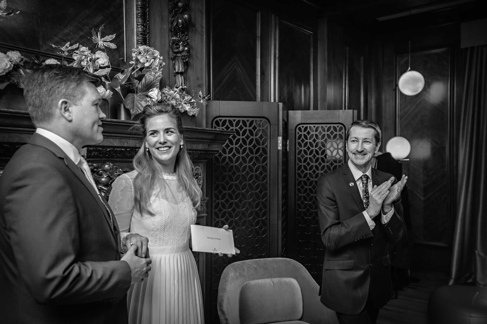 Wedding couple with their marriage certificate at their ceremony with registrar clapping