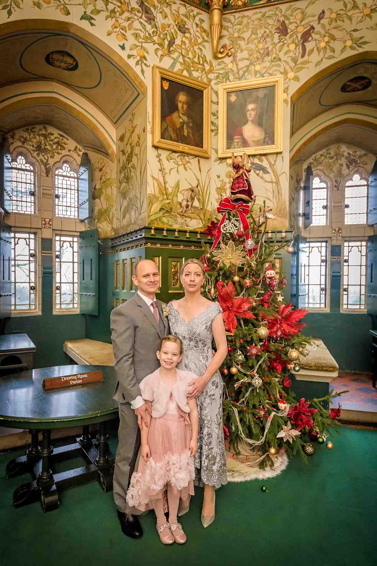 Wedding couple with daughter pose in front of Christmas Tree in the drawing room at Castell Coch