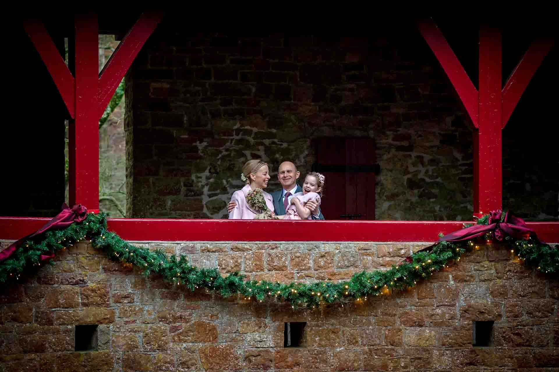 Bride, groom and daughter on balustrade of Castell Coch with Christmas decorations