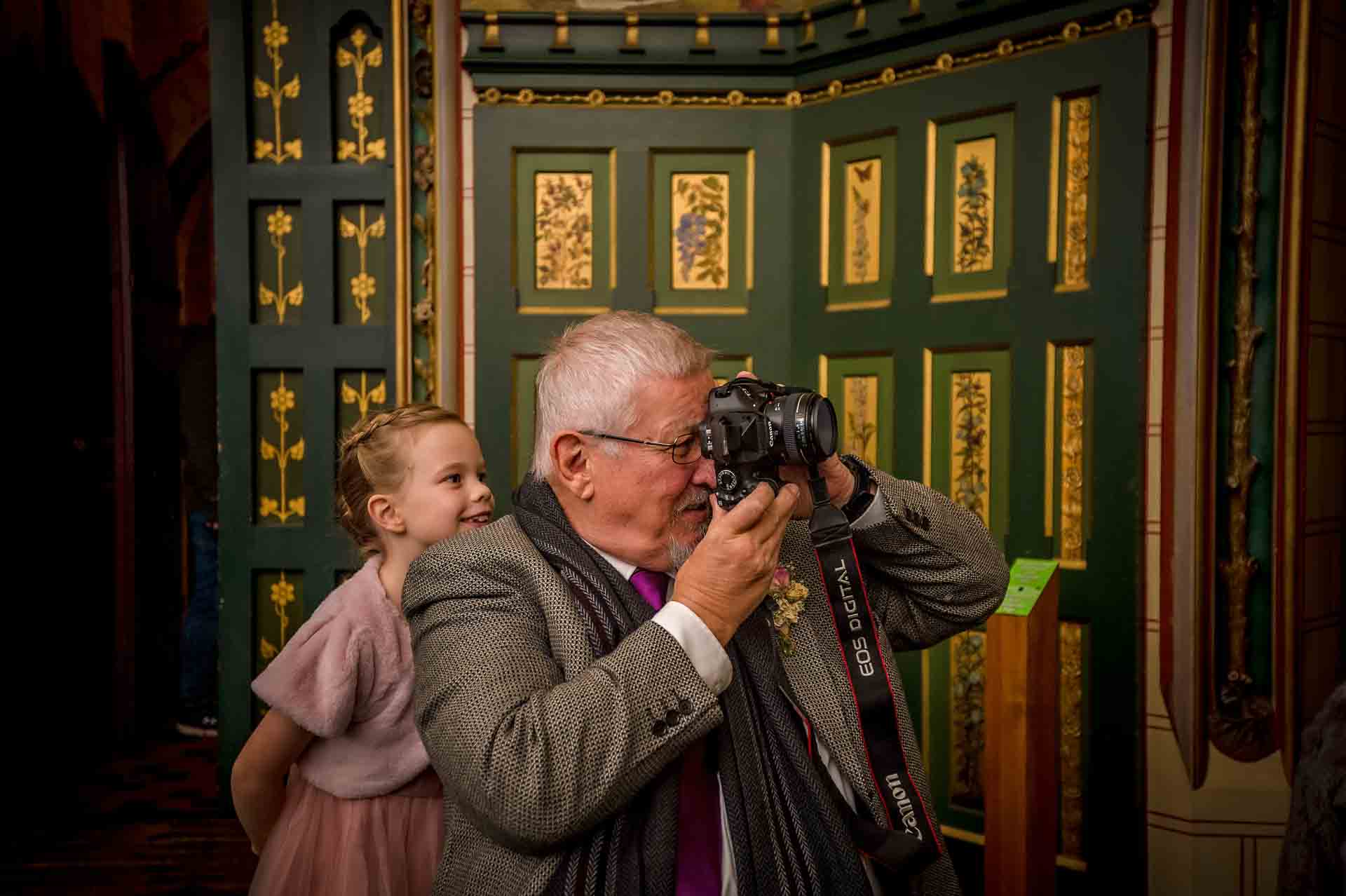 Grandfather takes photograph whilst granddaughter peers over his shoulder