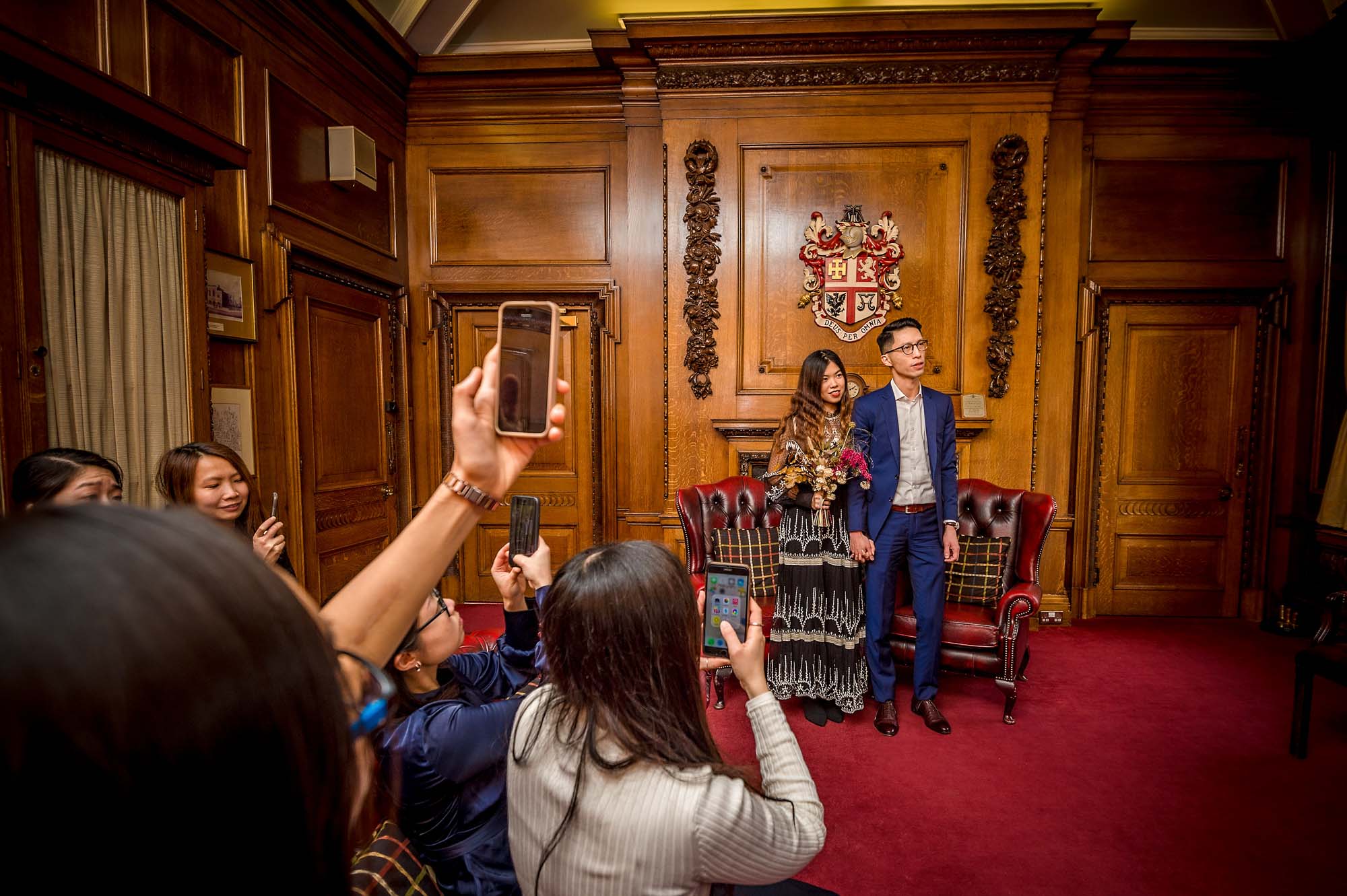 Guests filming couple on mobile phones at wedding ceremony in Islington Town Hall, London