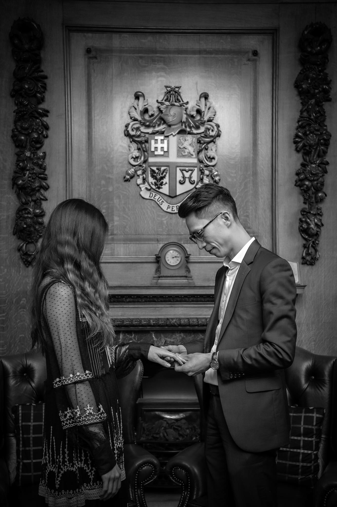 The groom places ring on bride's finger - black and white wedding portrait
