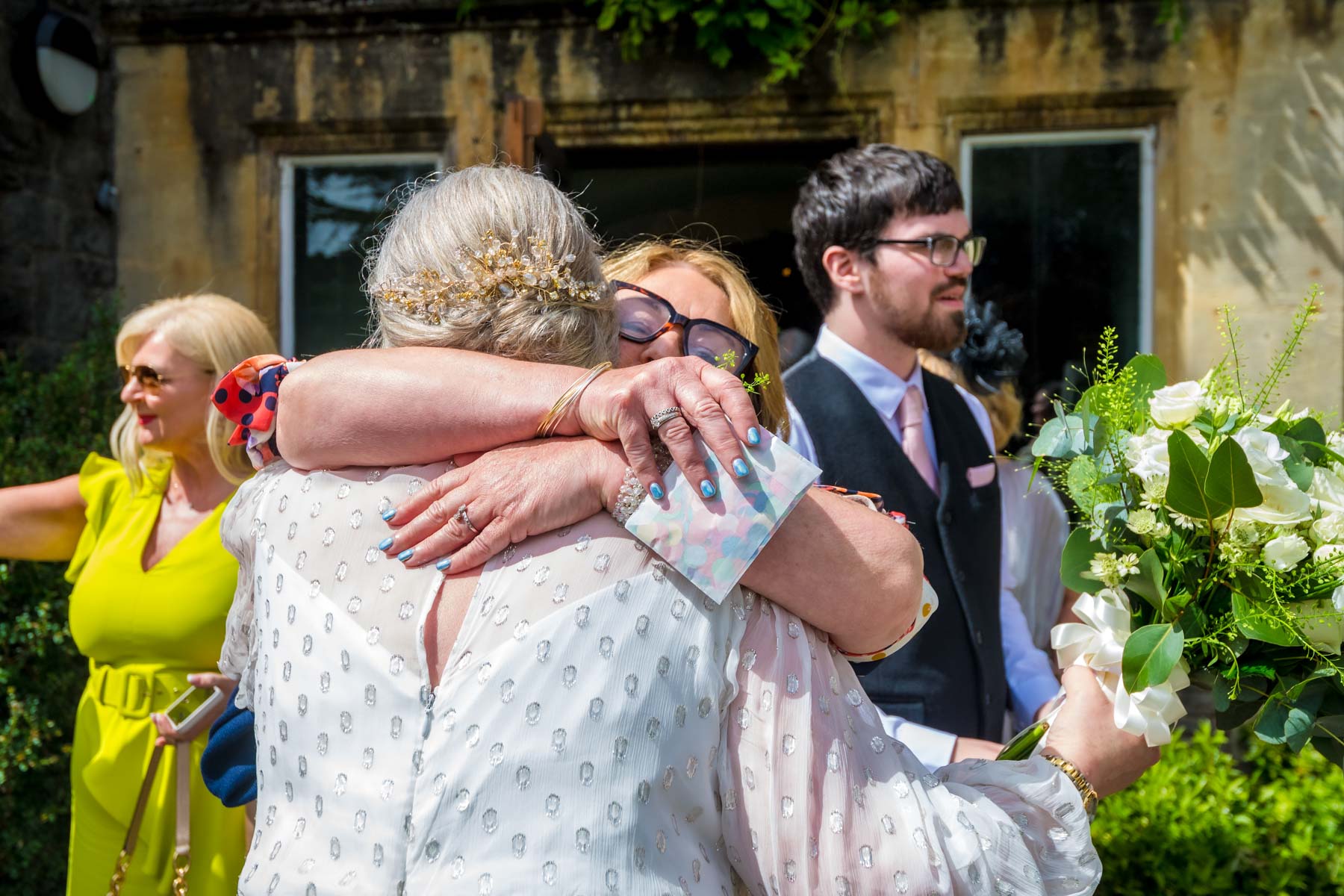 Bride from the back hugging female guest after wedding ceremony