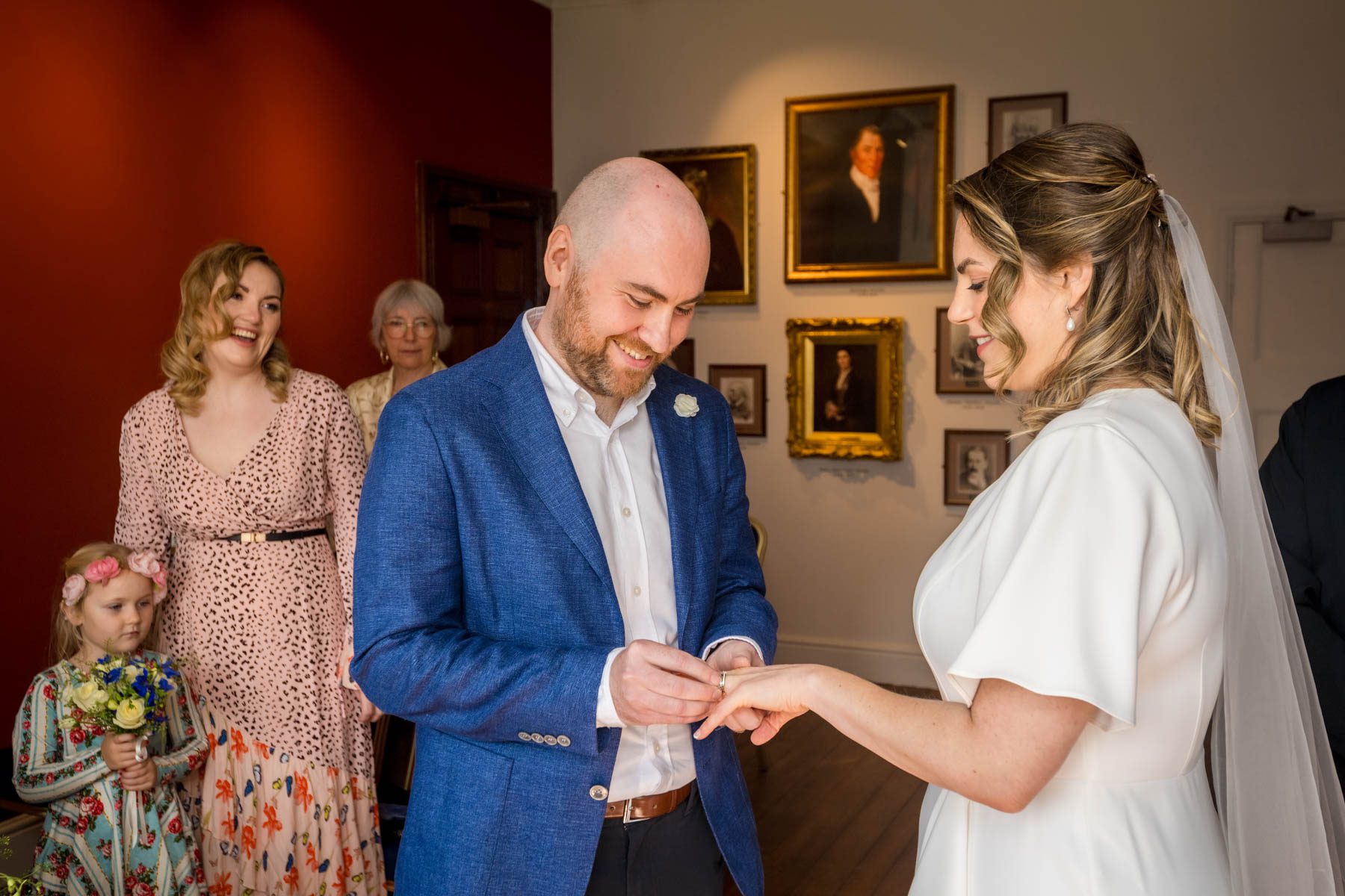 Happy groom placing ring on finger of bride at Insole Court wedding