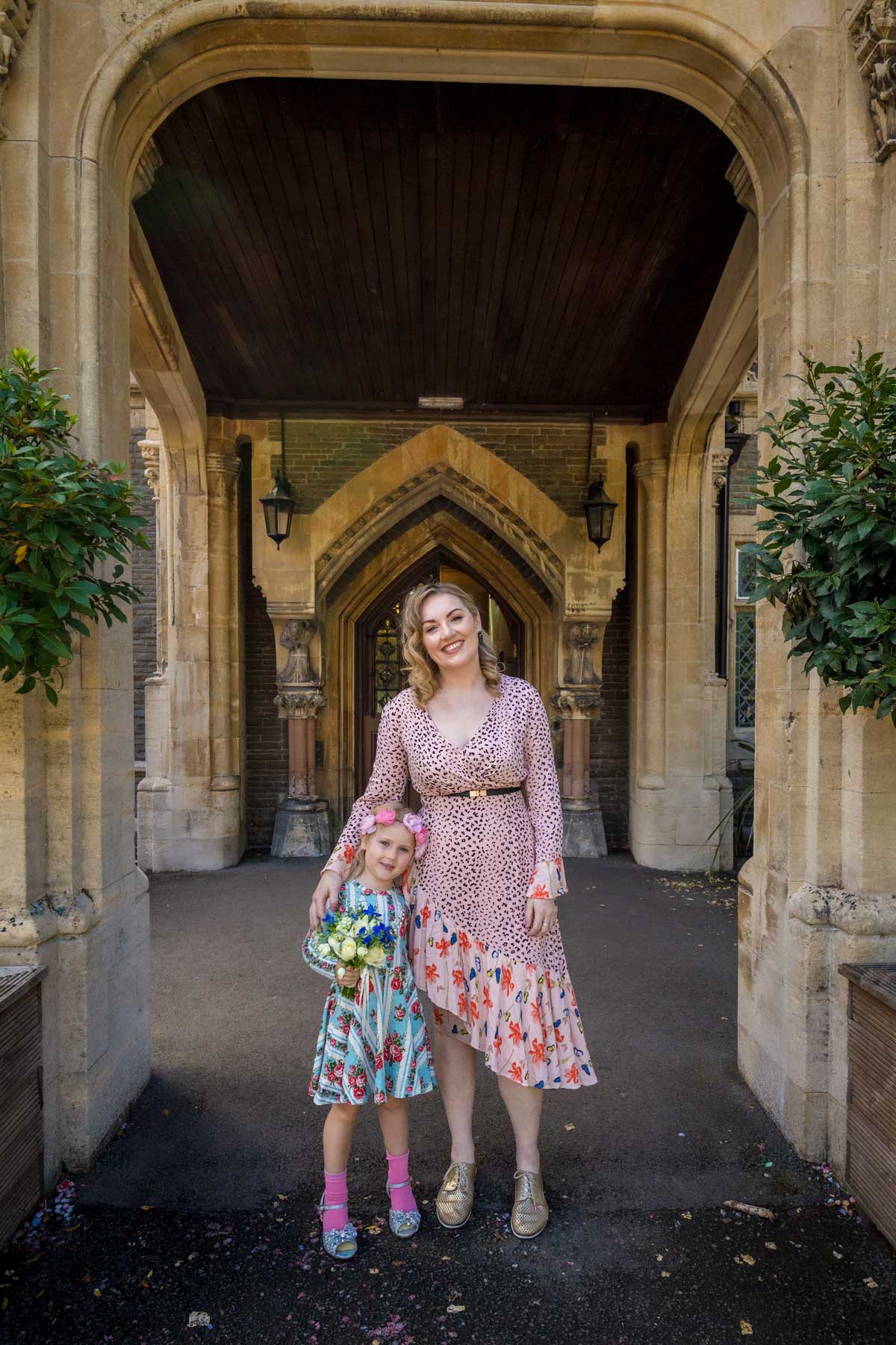 Female wedding guest and small girl pose for camera under portico at Insole Court in Cardiff