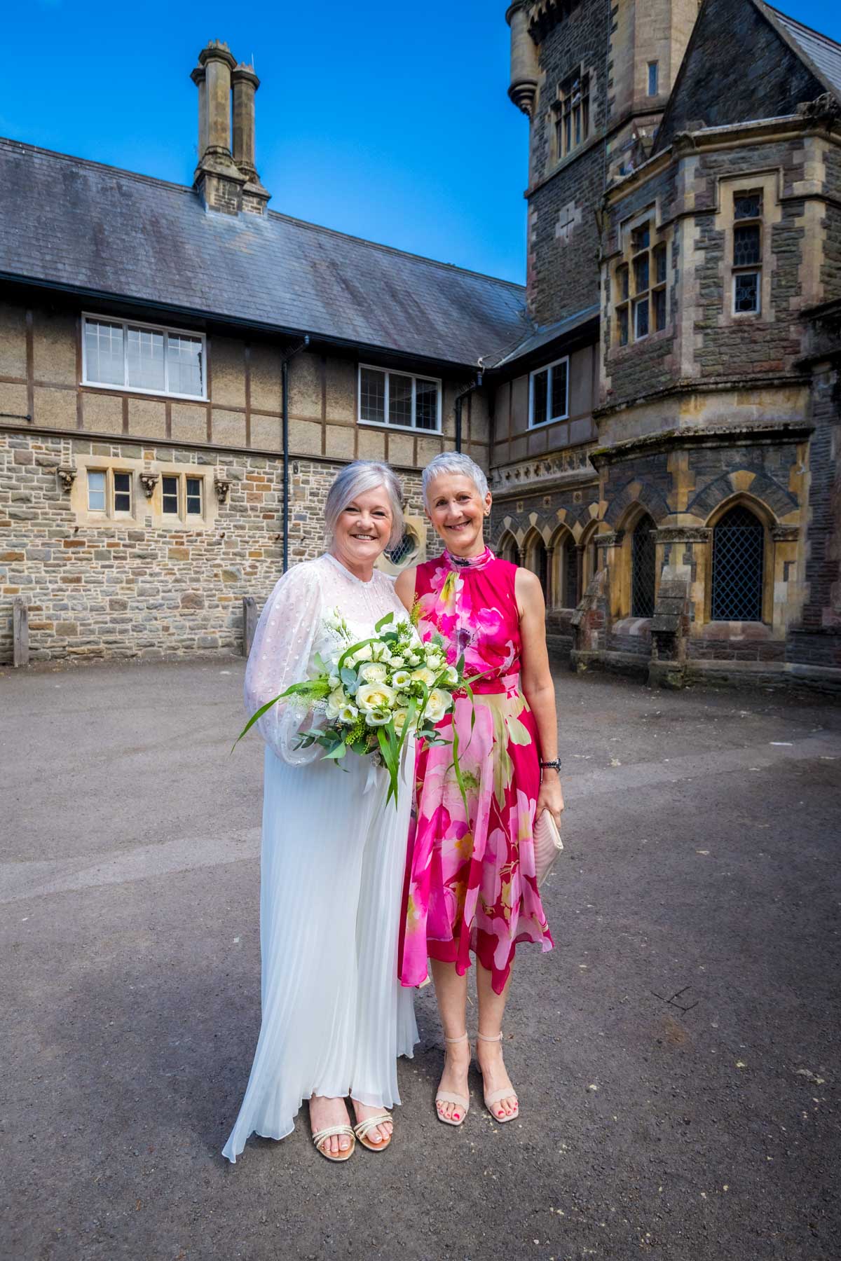Bride poses with female wedding guest outside Insole Court