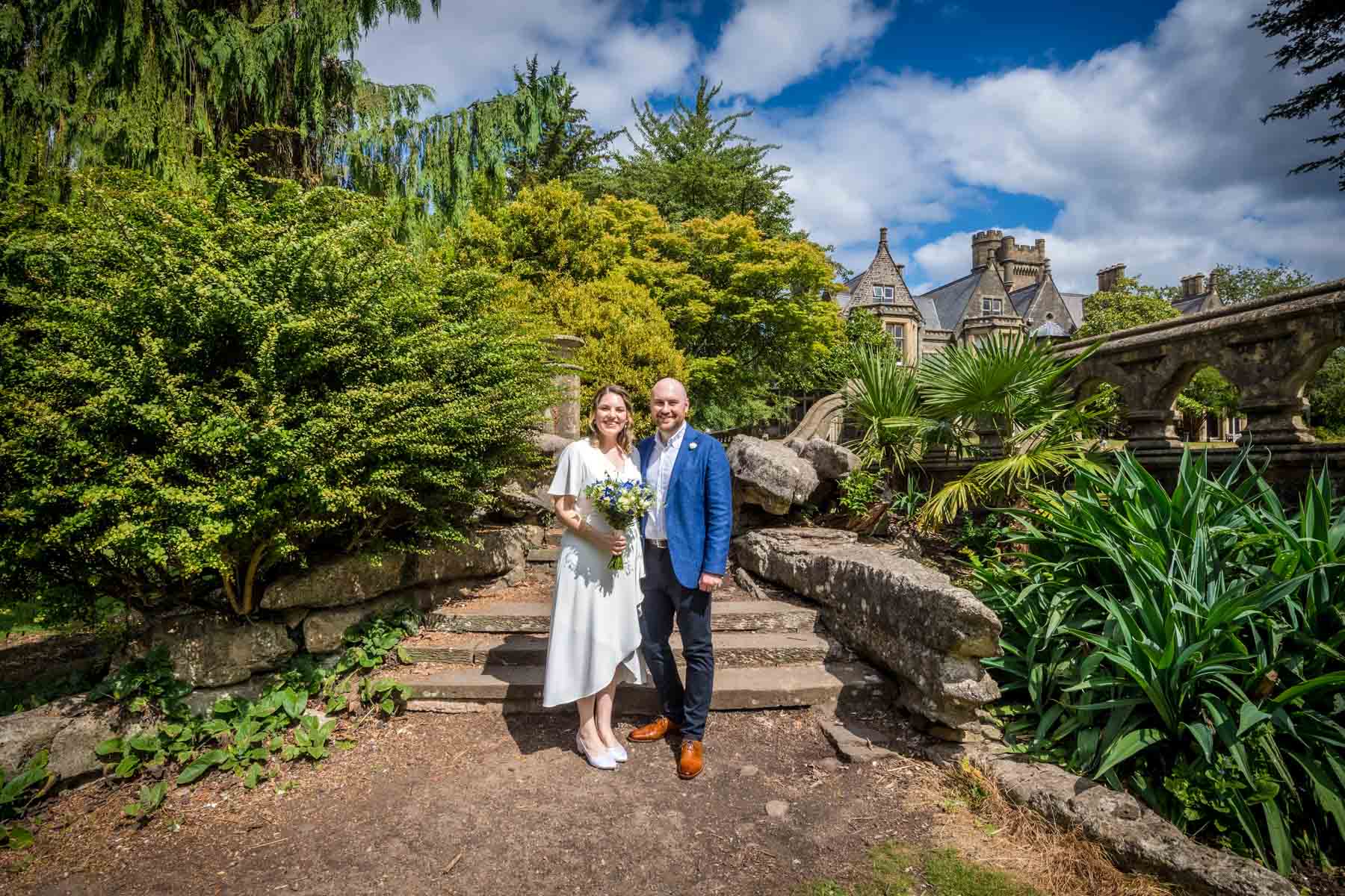 Bride and groom posing in gardens of InsoleCourt with house in the background