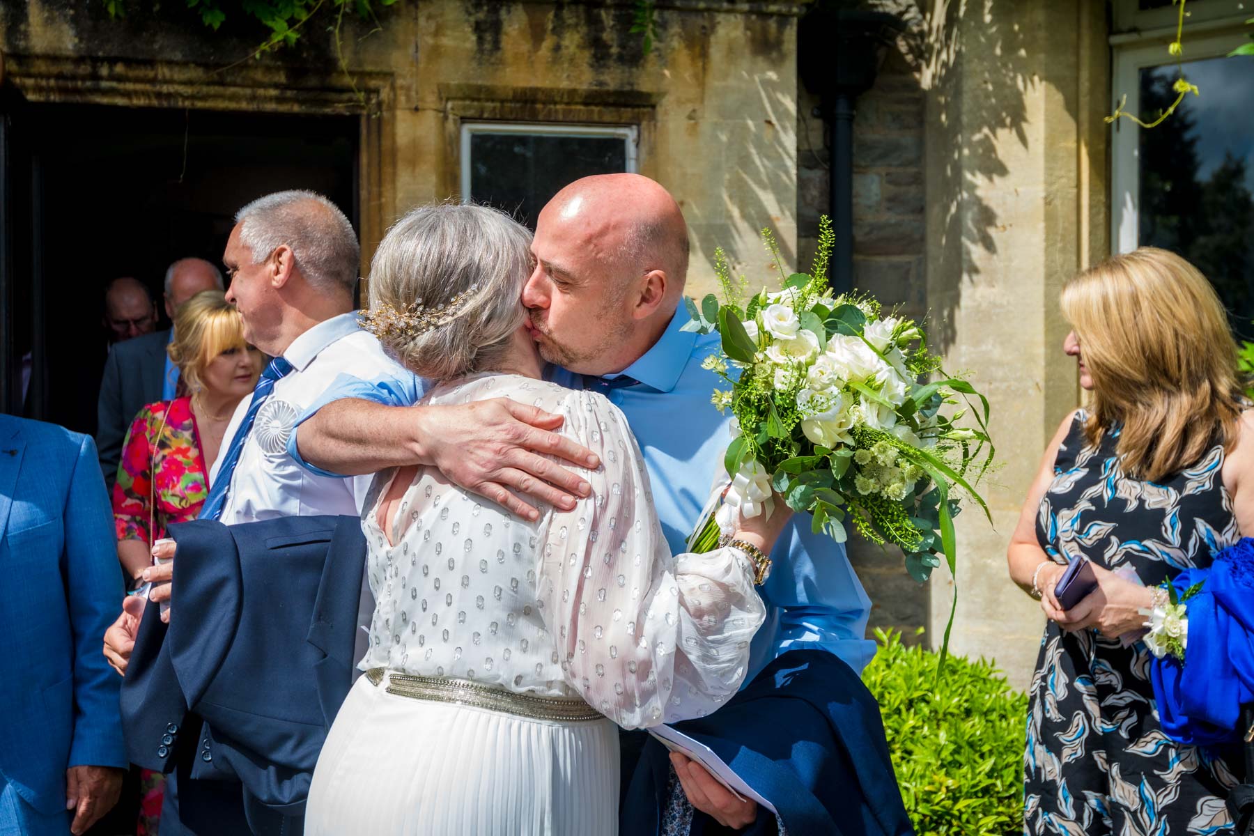 Guests Waiting Before Ceremony Wedding guest hugging bride in the sunshine