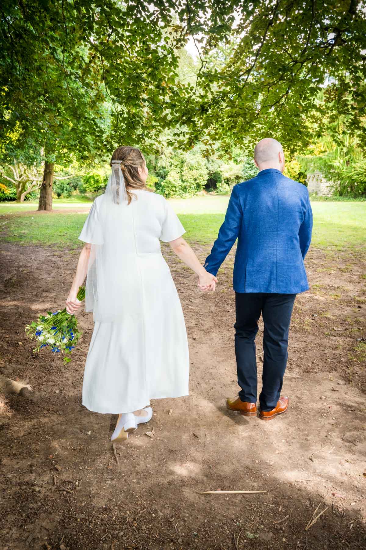 Newlywedded couple holding hands and walking away from camera at Cardiff Register Office