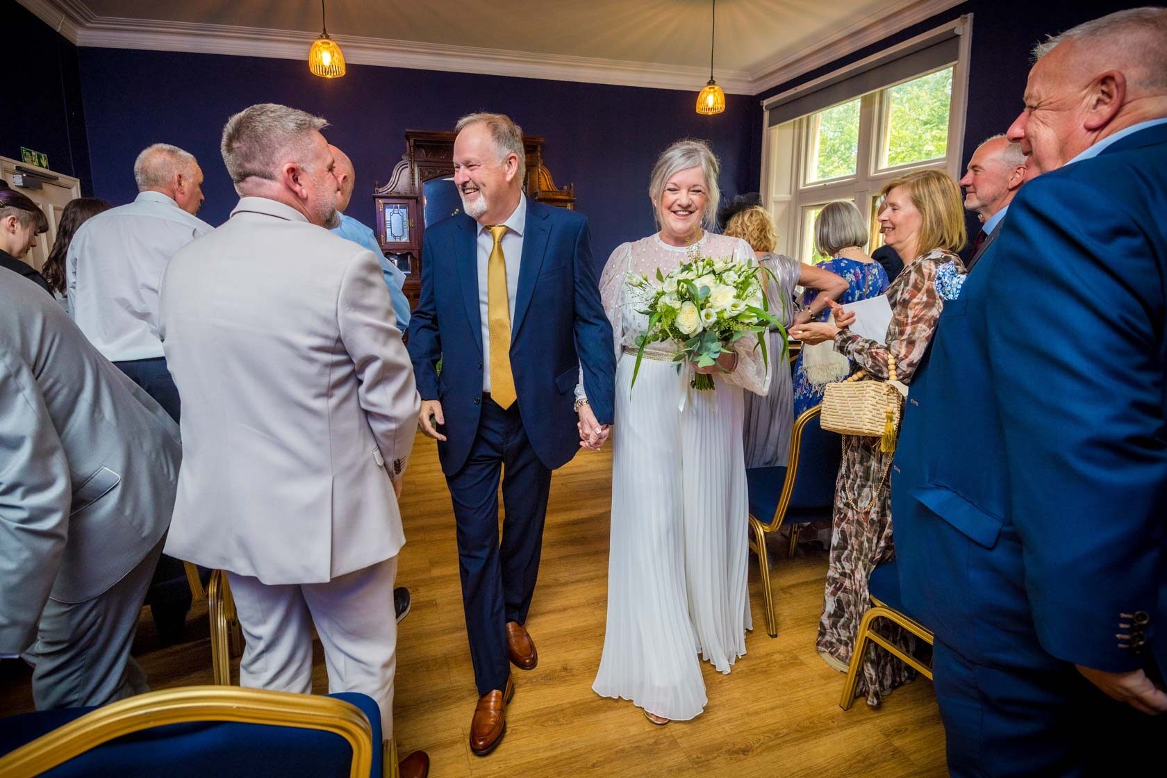 A smiling couple walk back up the aisle together after their Insole Court wedding