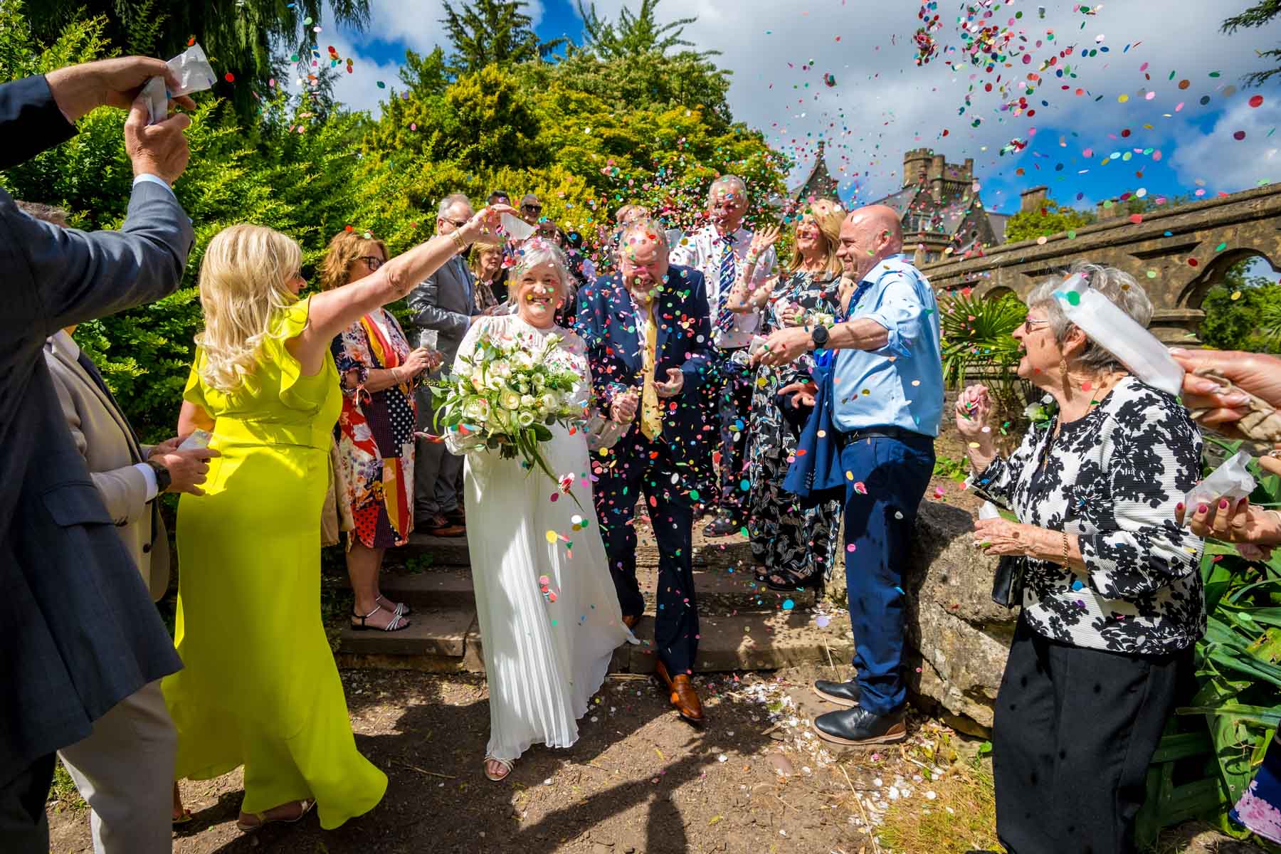 Couple passing through guests as they throw confetti in gardens of Insole court in Cardiff