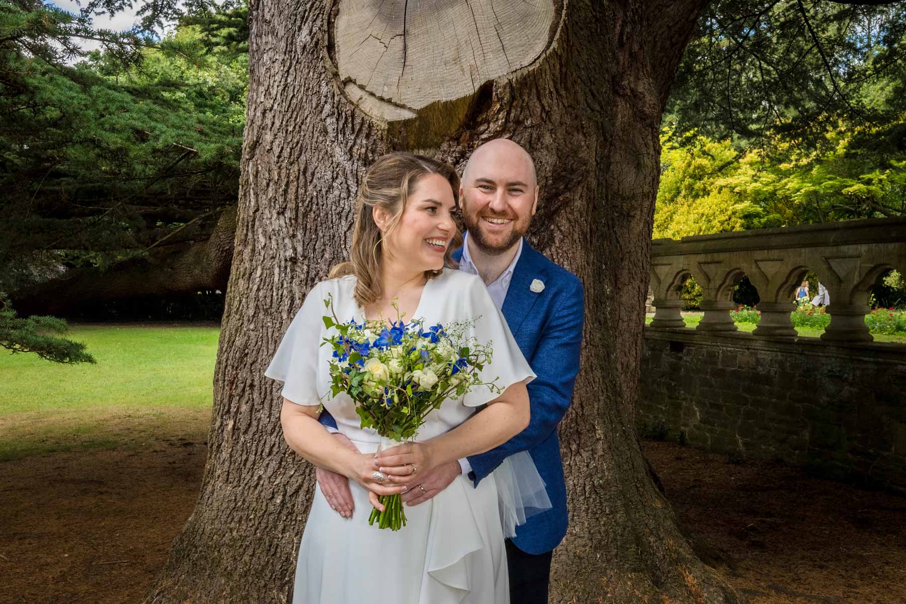 Newlyweds laughing under cedar tree at their Cardiff wedding