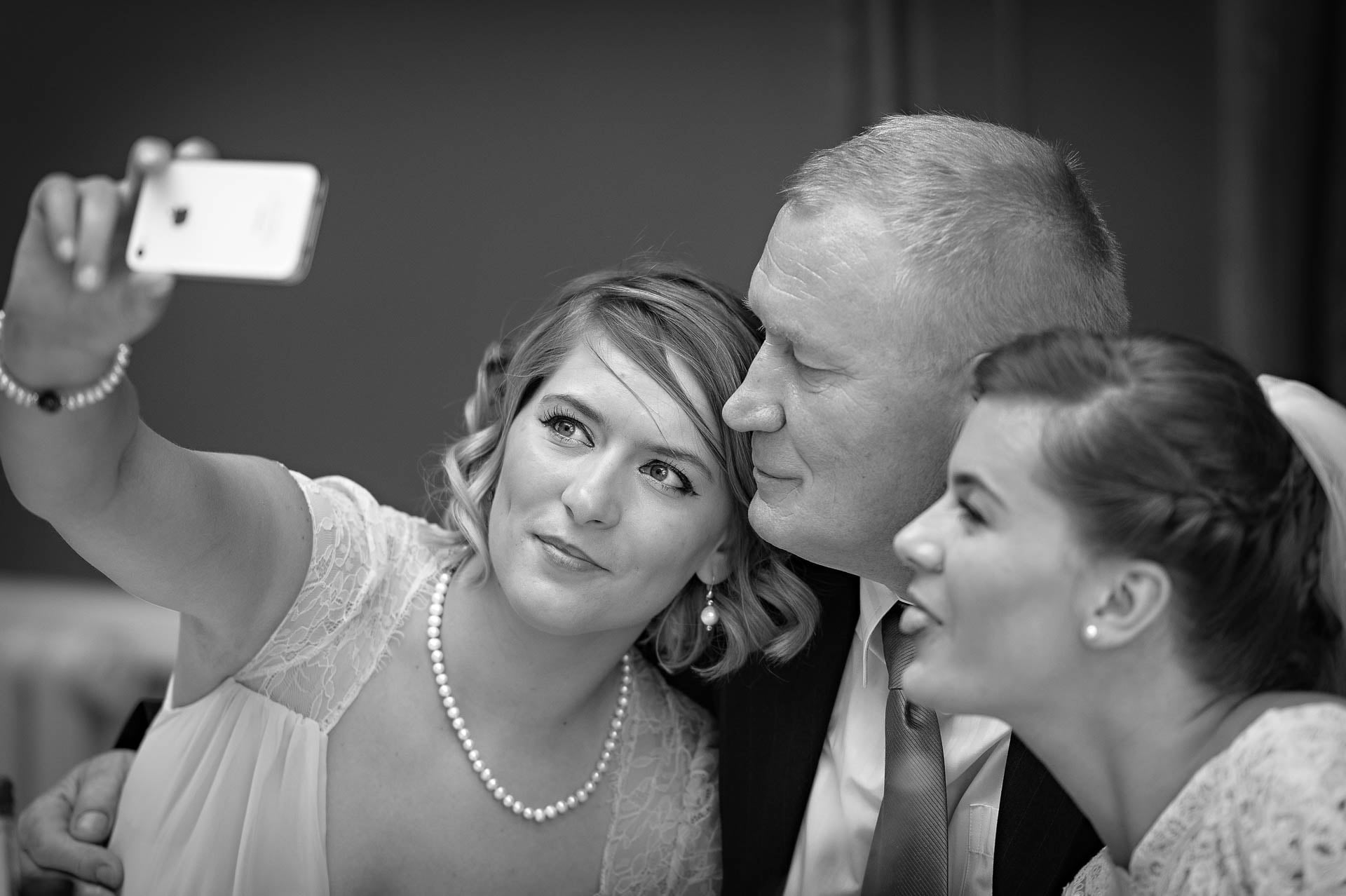 Bridesmaid takes selfie with bride and father at Hampton Court House wedding