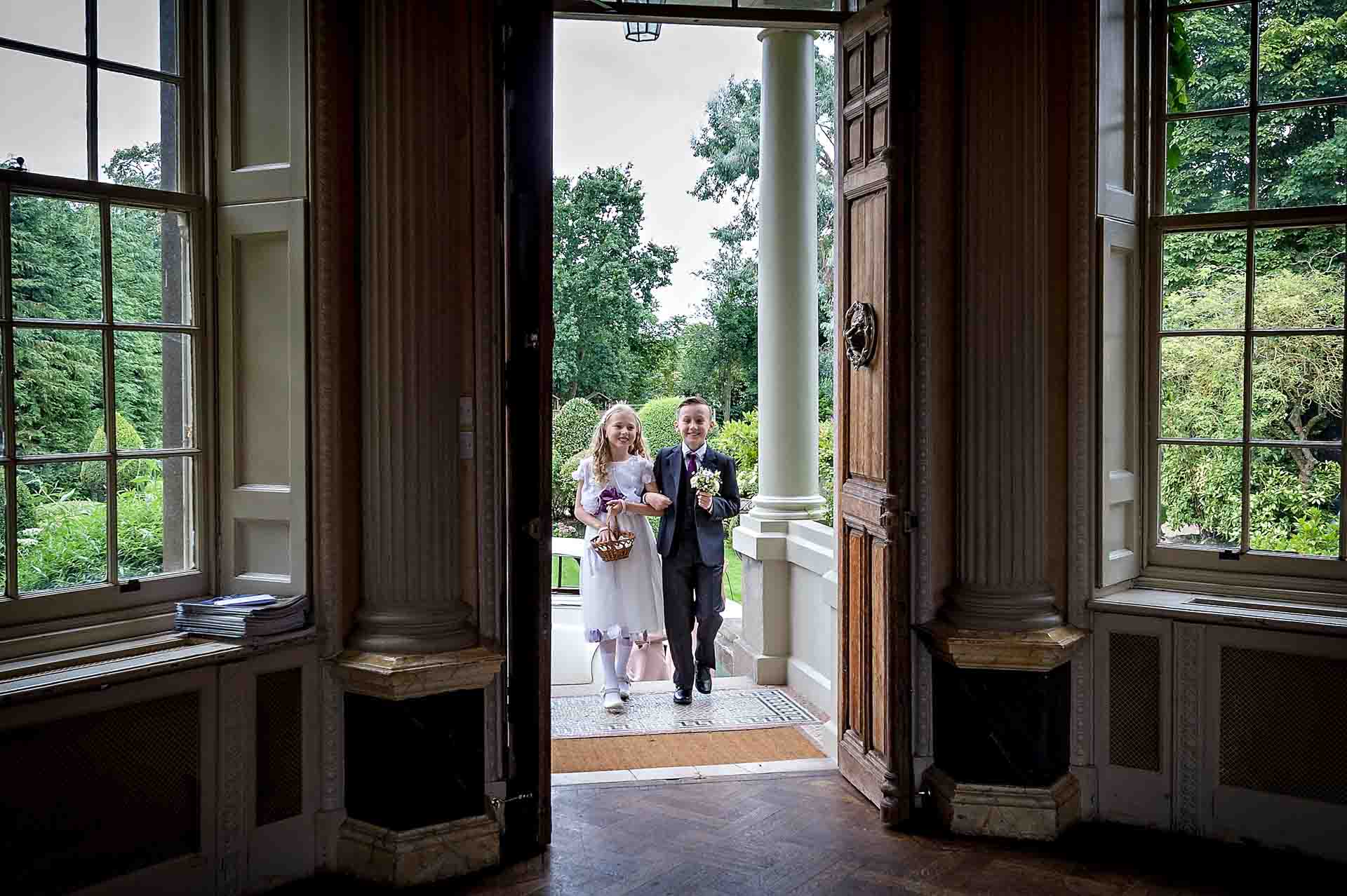 Bridesmaid and pageboy entering doors at Hampton Court House wedding