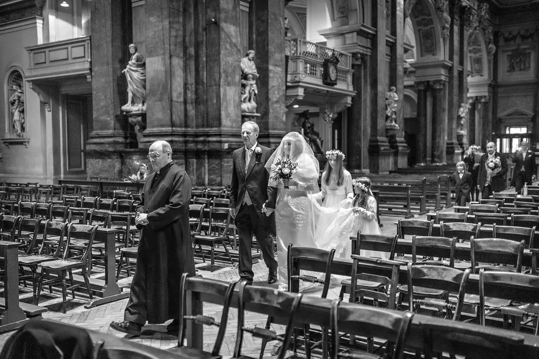 The bridal party is led down the aisle by the Head Sacristan at Brompton Oratory