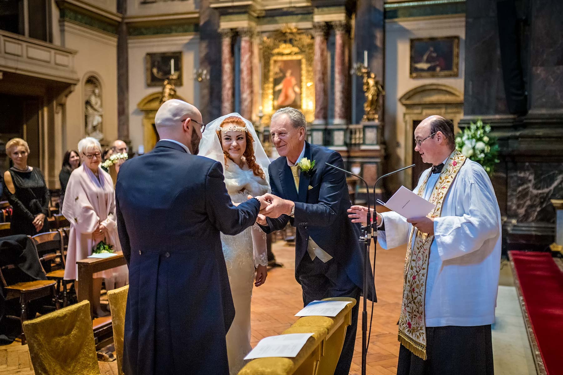 The bride's father gives away the bride to her groom at a Brompton Oratory wedding ceremony