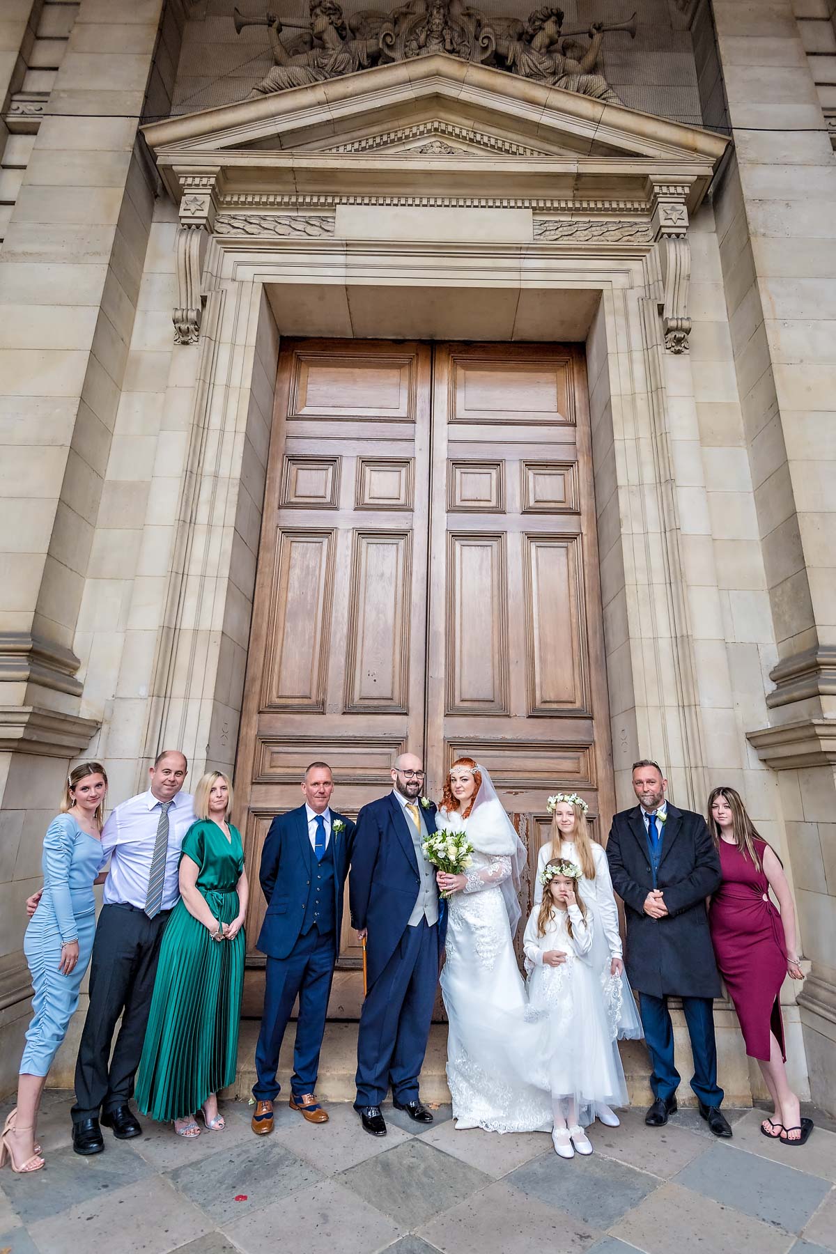 Wedding guests pose with couple outside the Brompton Oratory main doors