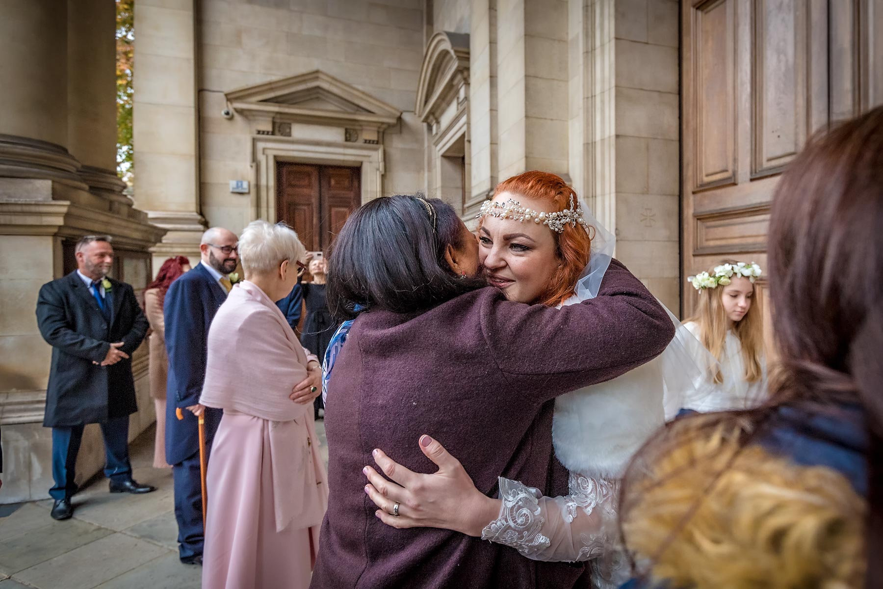 The bride hugs a guest outside Brompton Oratory after her marriage ceremony