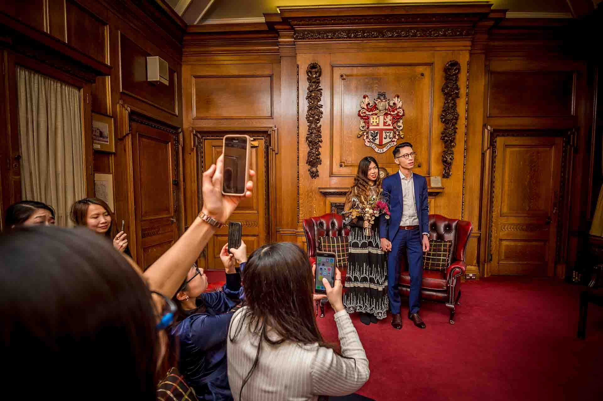 Guests taking wedding ceremony photos on their phones in the Mayor's Parlour in Islington