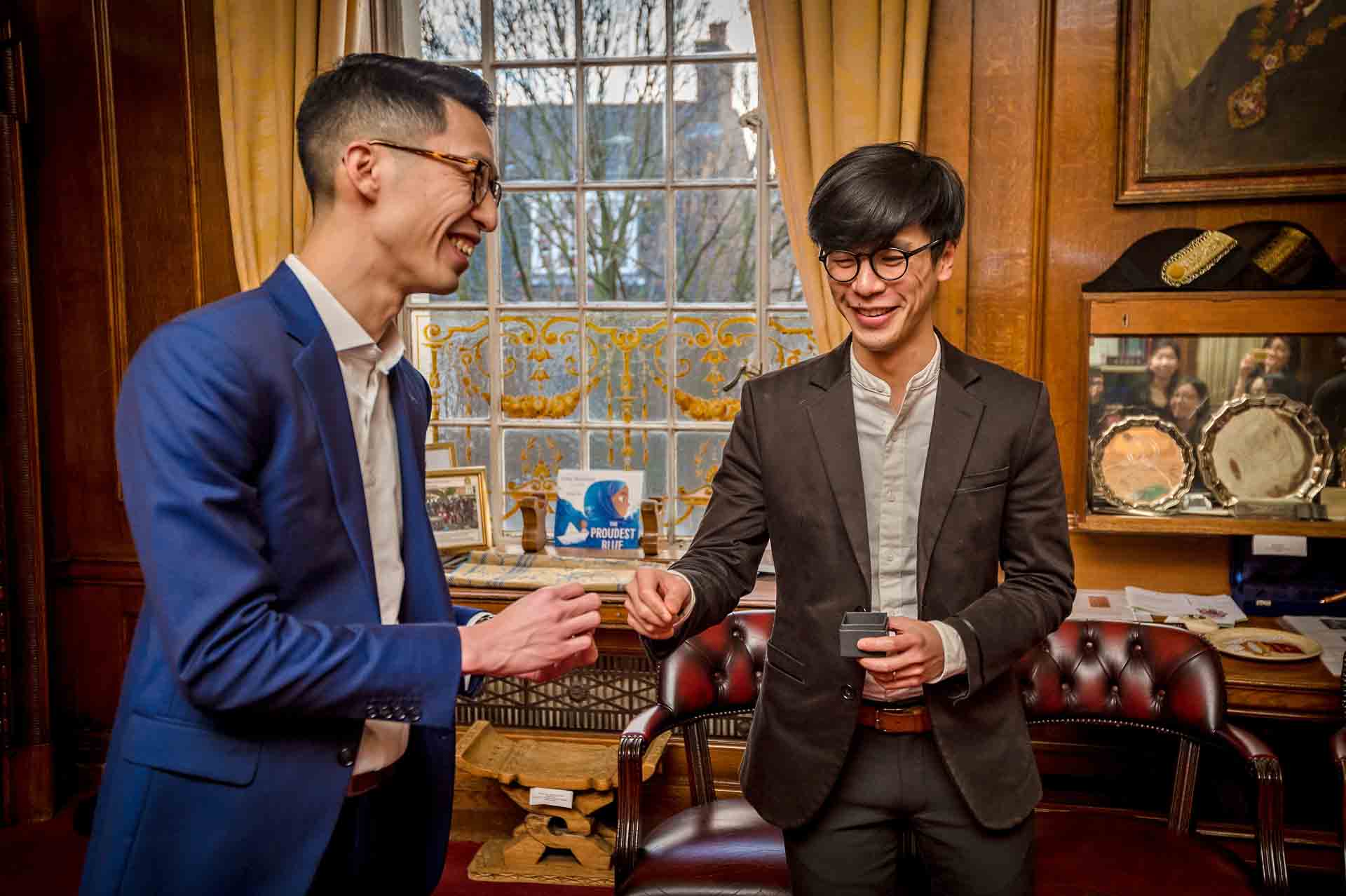 The smiling ring bearer hands the groom his ring at a wedding in London