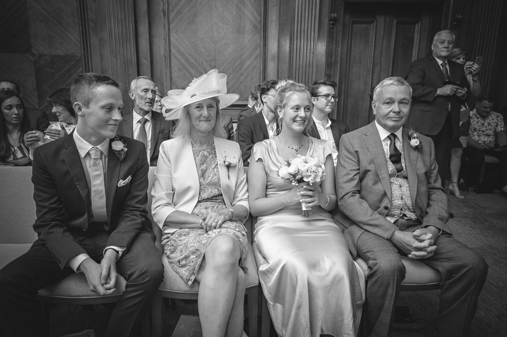 Four wedding guests in front rown of marriage at Old Marylebone Town Hall, London