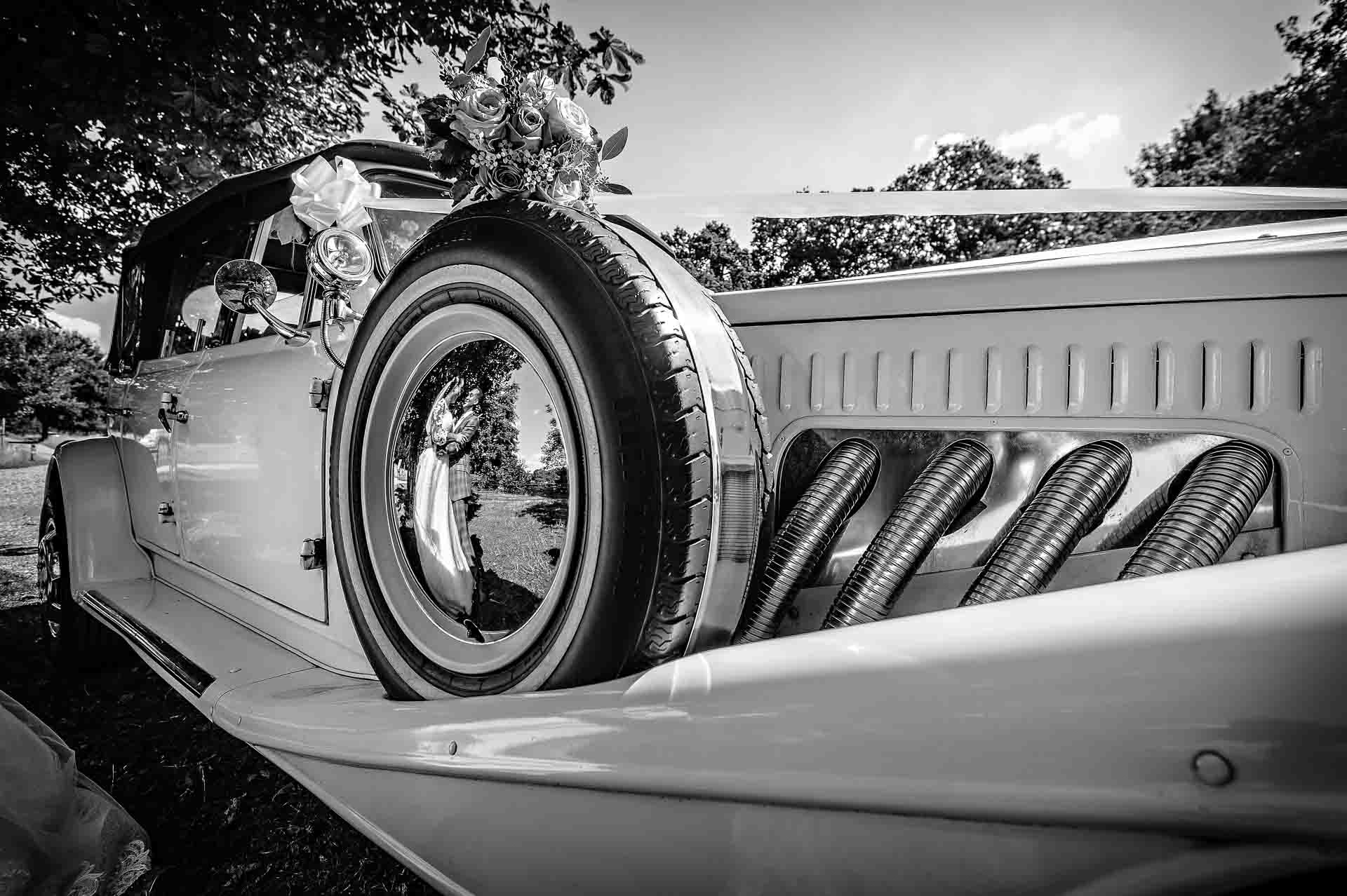 Vintage car with bride & groom reflected in spare tyre