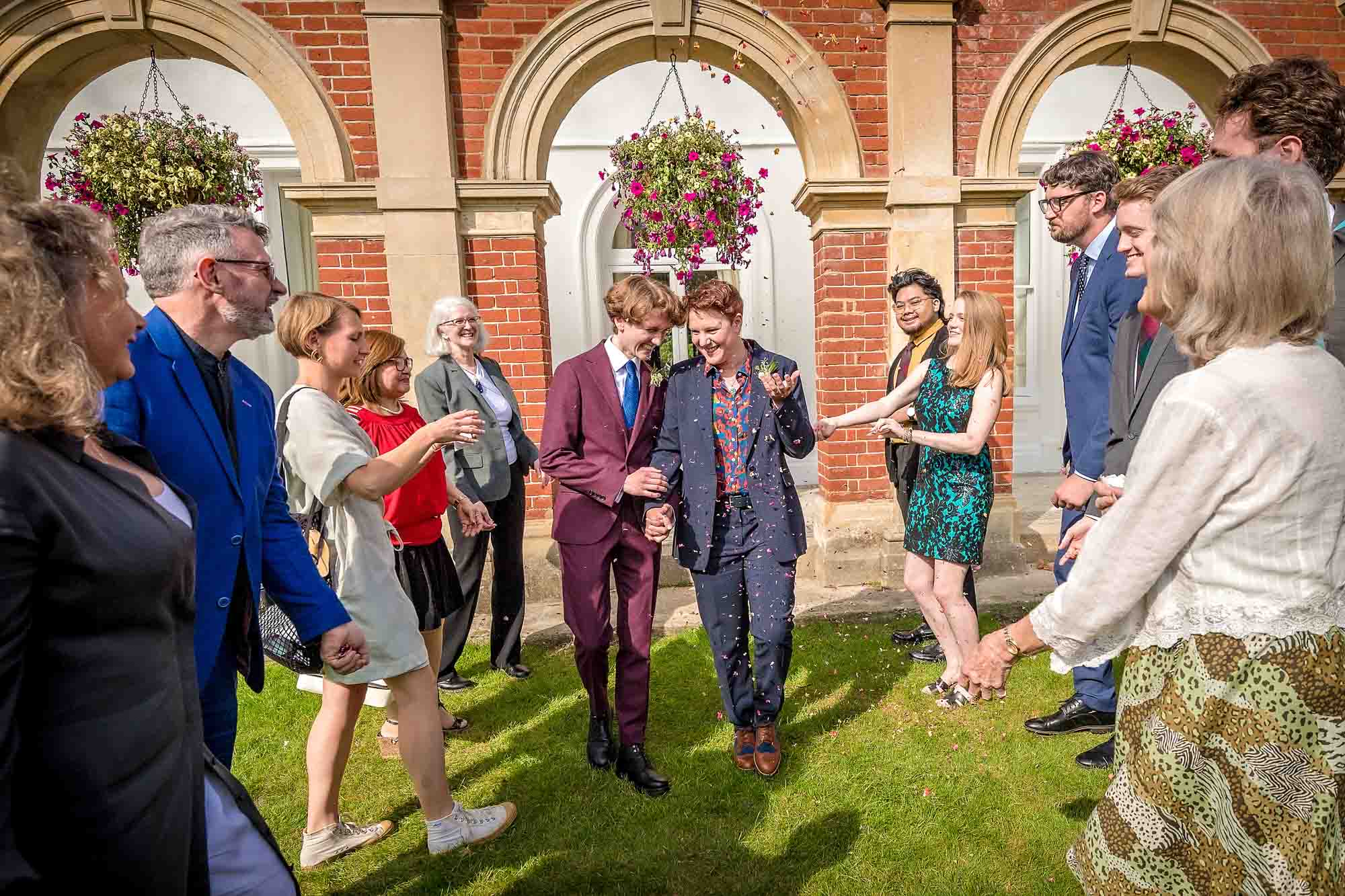 Guests throwing confetti over same-sex brides in gardens of Bromley Civic Centre