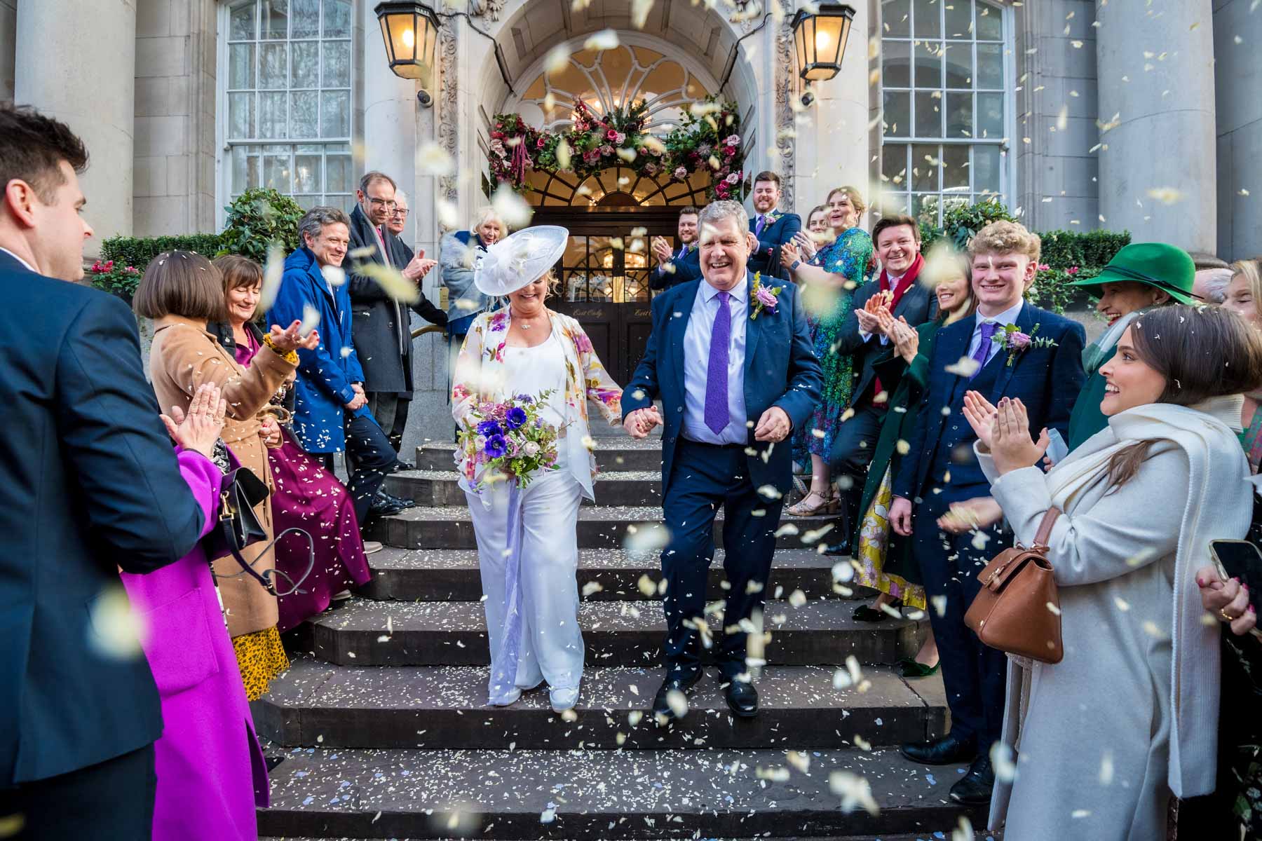 Mature wedding couple walking down steps outside Chelsea Old Town hall in a flurry of confetti