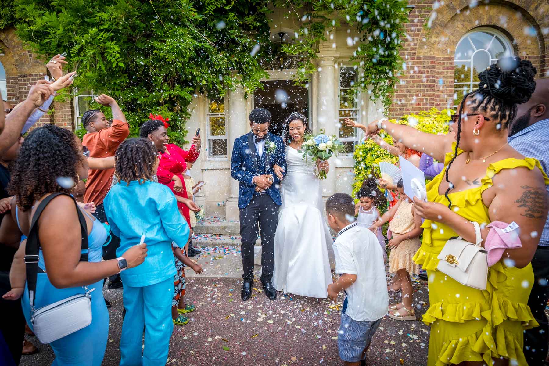 Couple getting covered in confetti by throwing guests at Morden Park House