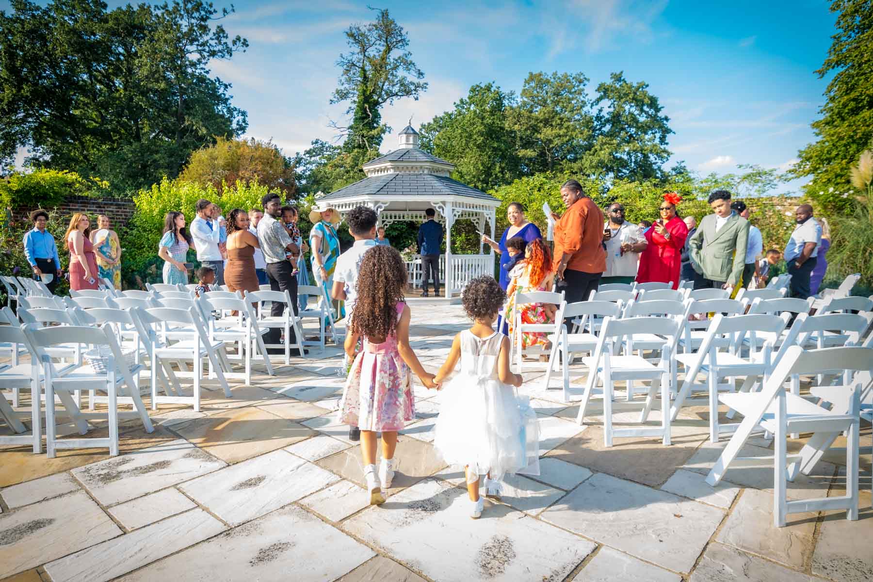 Two girls walking down the aisle from behind towards the Gazebo at a Morden Park House wedding