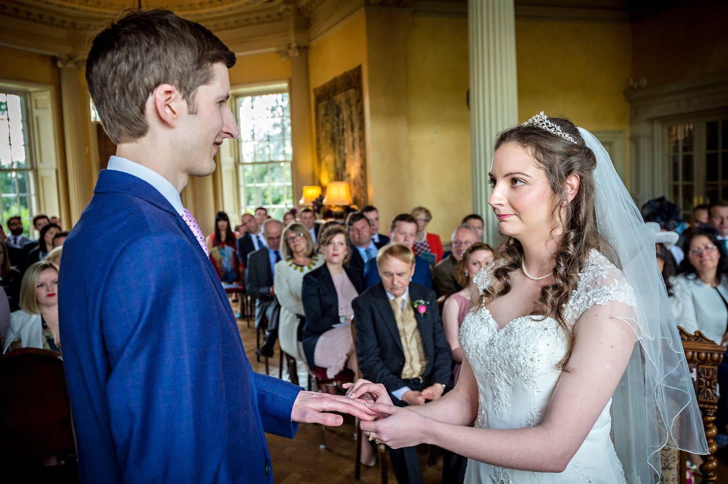 The bride places a ring on her groom's finger at Hampton Court House