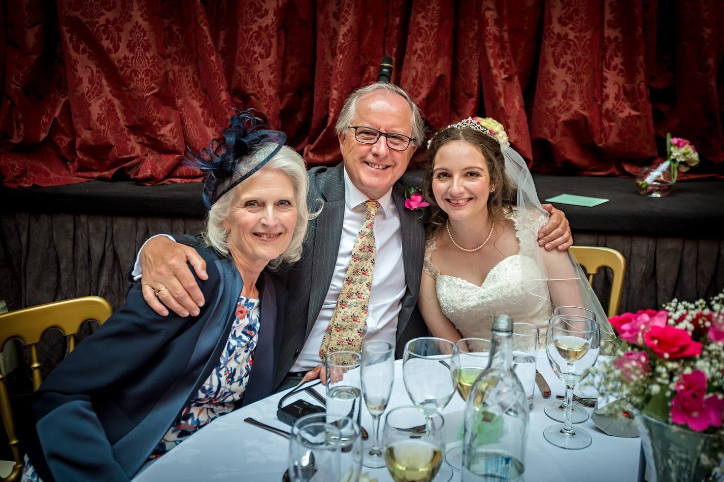 Bride with parents at wedding reception in Hampton Court House