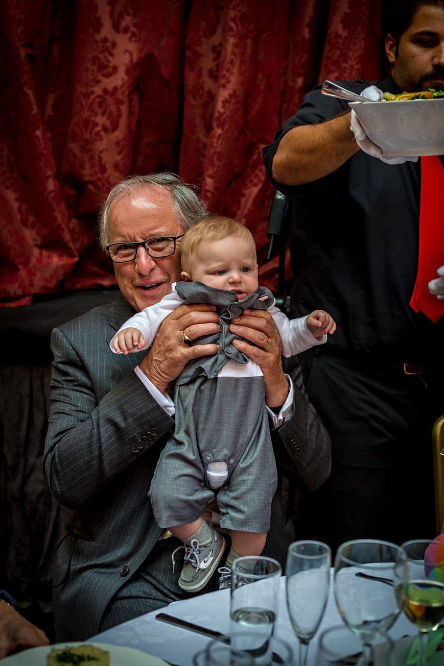 Grandfather lifting grandson at wedding reception