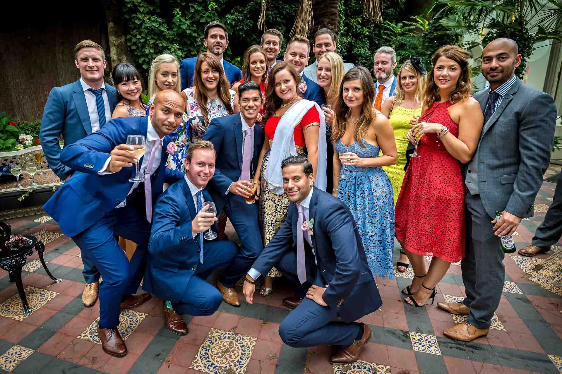 Large group of guests posing at wedding on patio of Hampton Court House