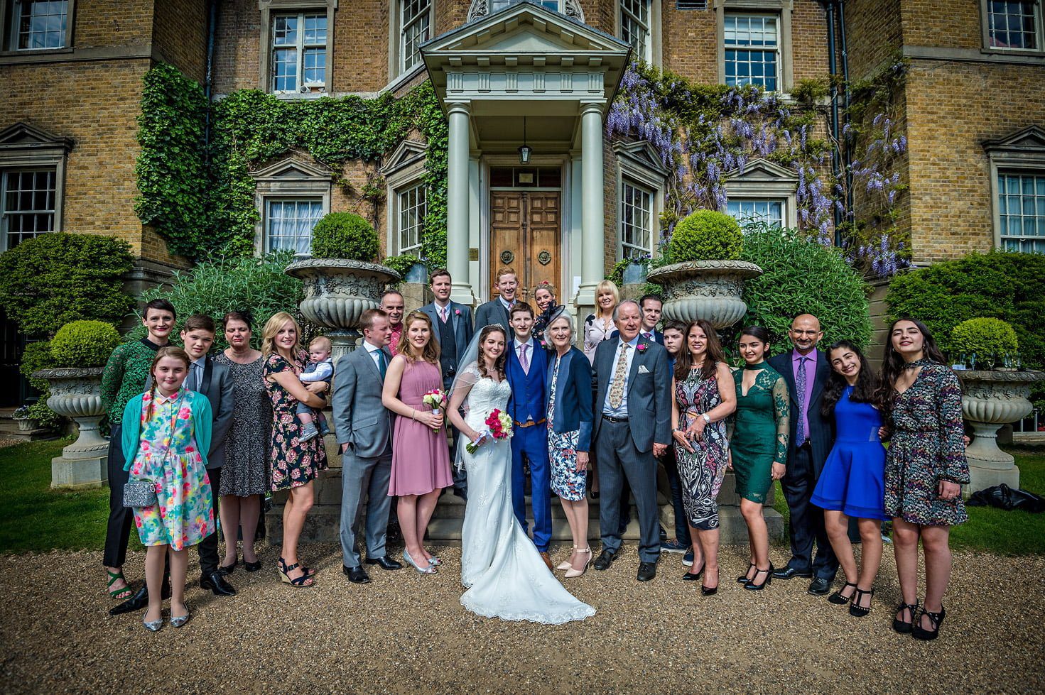 Group wedding photo outside the front of Hampton Court House