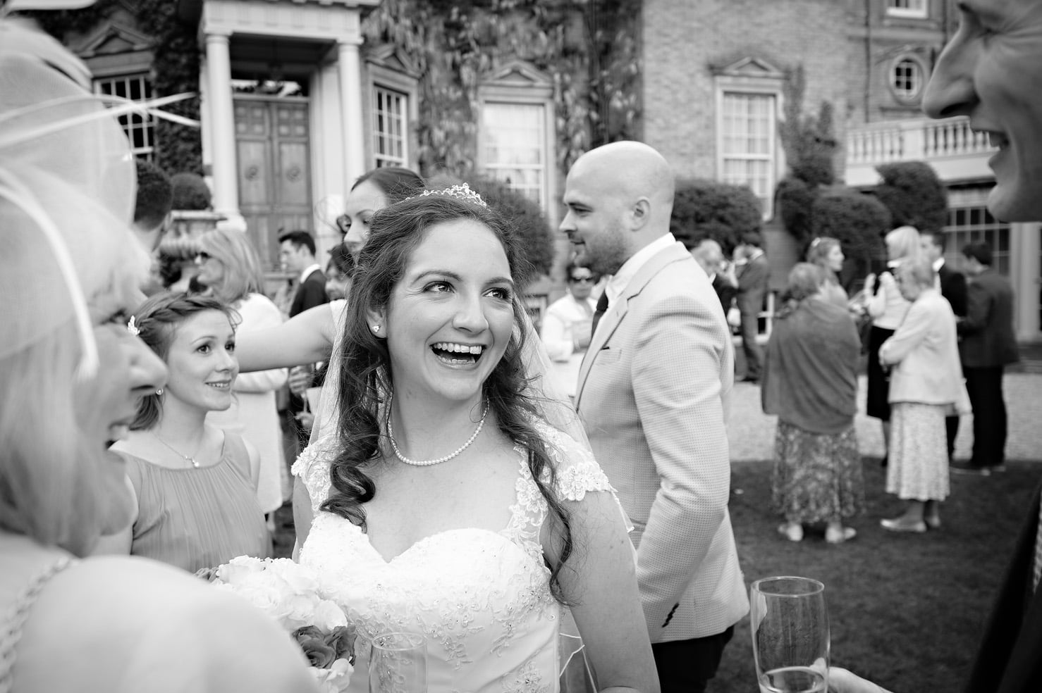 Bride laughing at drinks reception outside Hampton Court House