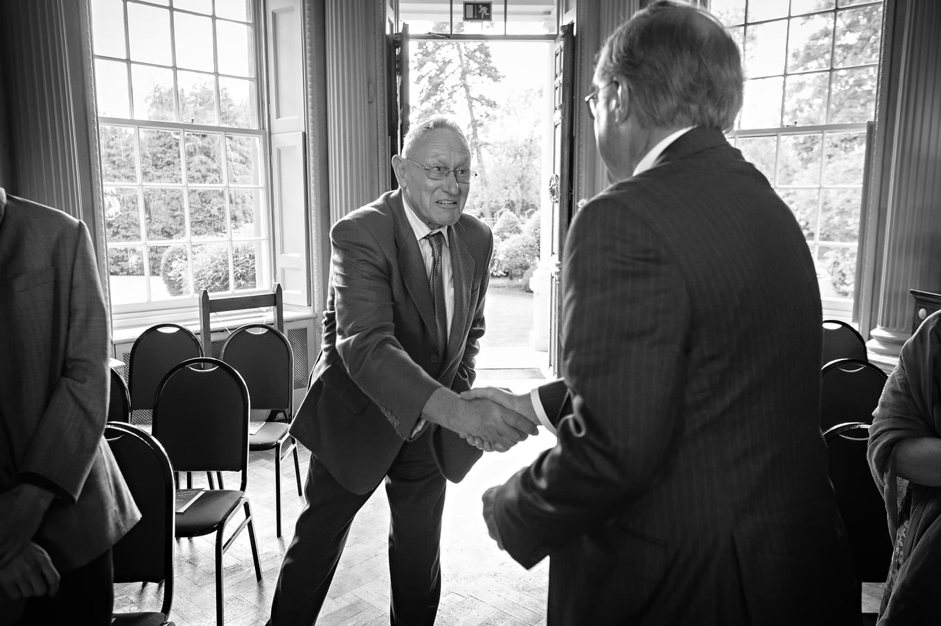 Two older male family members greeting each other at a Hampton Court House wedding