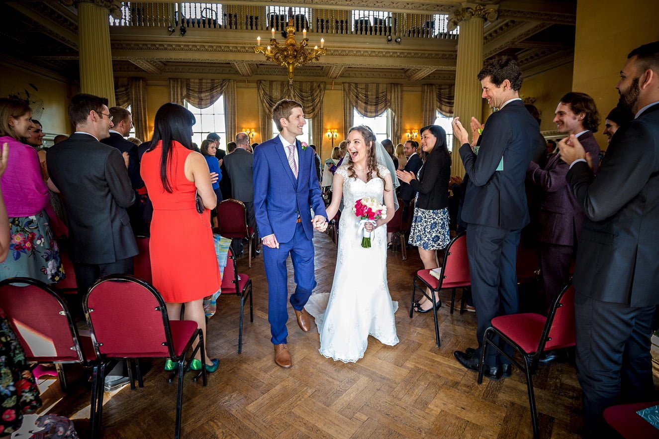 The newly-weds walk back up the aisle at their Hampton Court House wedding