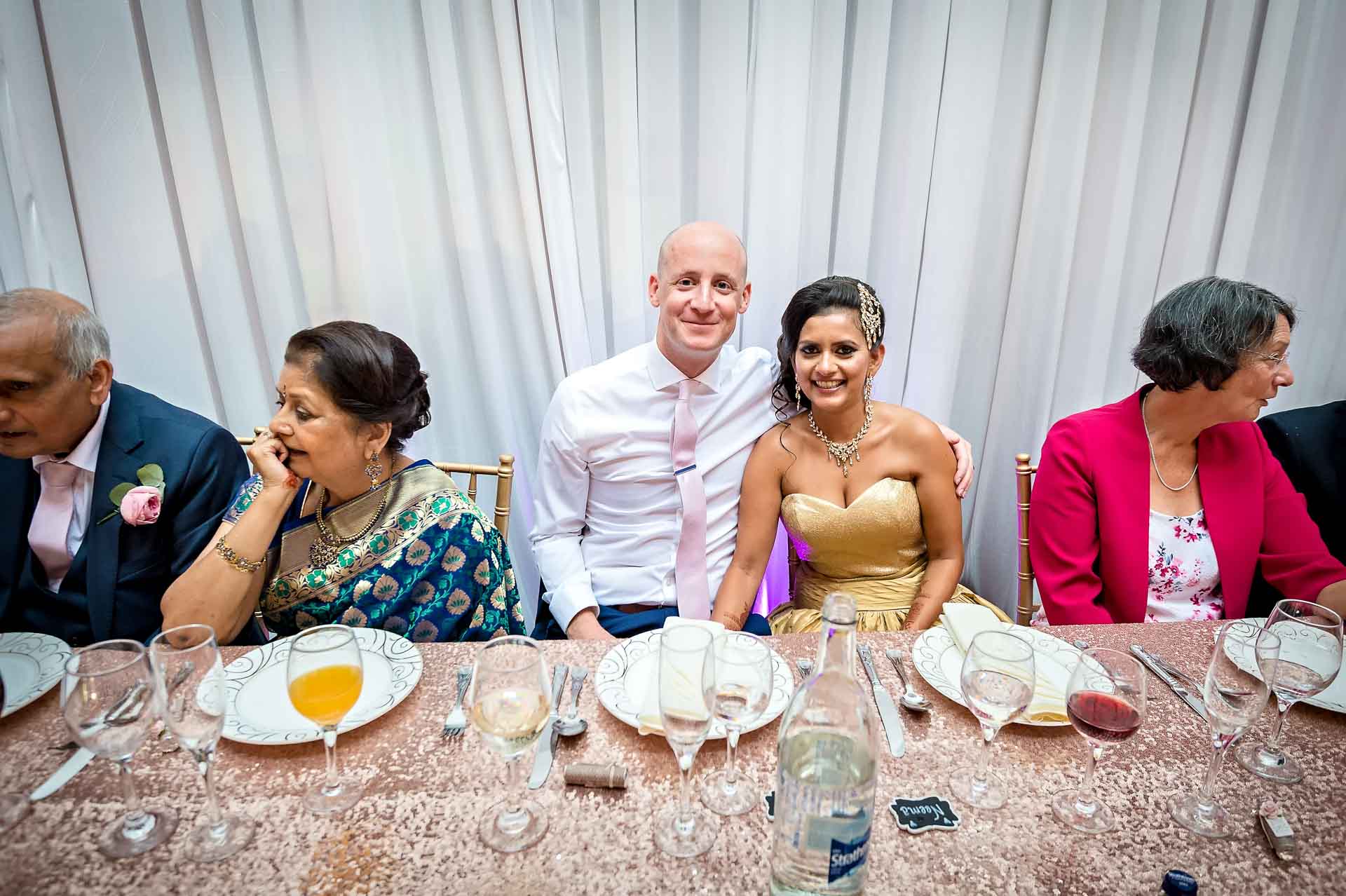 The newly-weds sitting at long table posing for photo